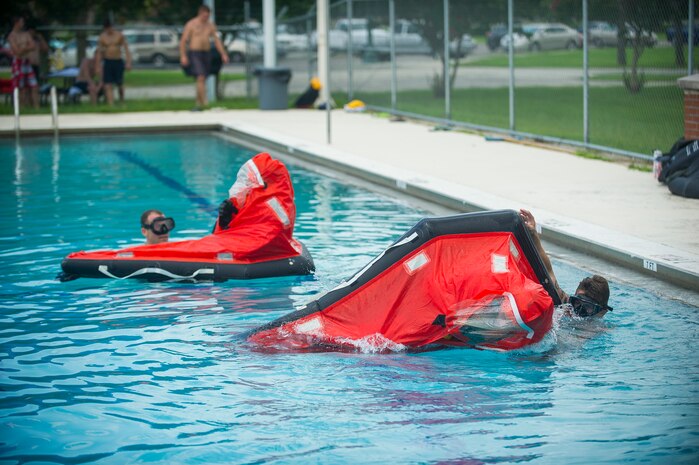 Petty Officer Toby Godwin and Chief Petty Officer Jason Counts, both instructors from the Naval Submarine School in Groton, Conn., assist Naval Nuclear Power Training Command students as they practice survival techniques inside a Submarine Escape Immersion Equipment suit July 17, 2014, at Joint Base Charleston, S.C Almost 150 enlisted NNPTC students received training on surface survival techniques and using SEIE. (U.S. Air Force photo/Senior Airman George Goslin)