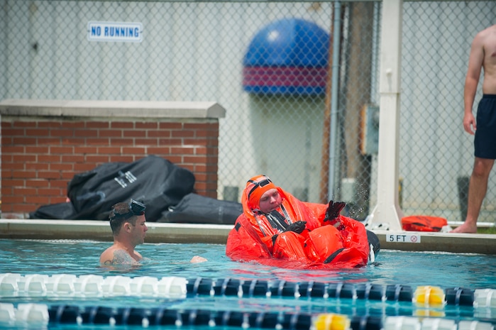 Chief Petty Officer Jason Counts, an instructor from the  Naval Submarine School in Groton, Conn., assists a Naval Nuclear Power Training Command student as he practices survival techniques inside a Submarine Escape Immersion Equipment suit July 17, 2014, at Joint Base Charleston, S.C Almost 150 enlisted NNPTC students received training on surface survival techniques and using SEIE. (U.S. Air Force photo/Senior Airman George Goslin)