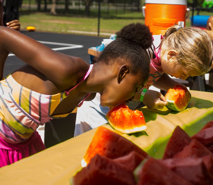 Taunya Thompson, left and Janay Hill, compete in a watermelon eating contest during the July Jamboree at Moody Air Force Base, Ga., July 22, 2014. Each contestant had to eat the watermelon as fast as possible without using their hands. (U.S. Air Force photo by Airman 1st Ceaira Tinsley/Released)