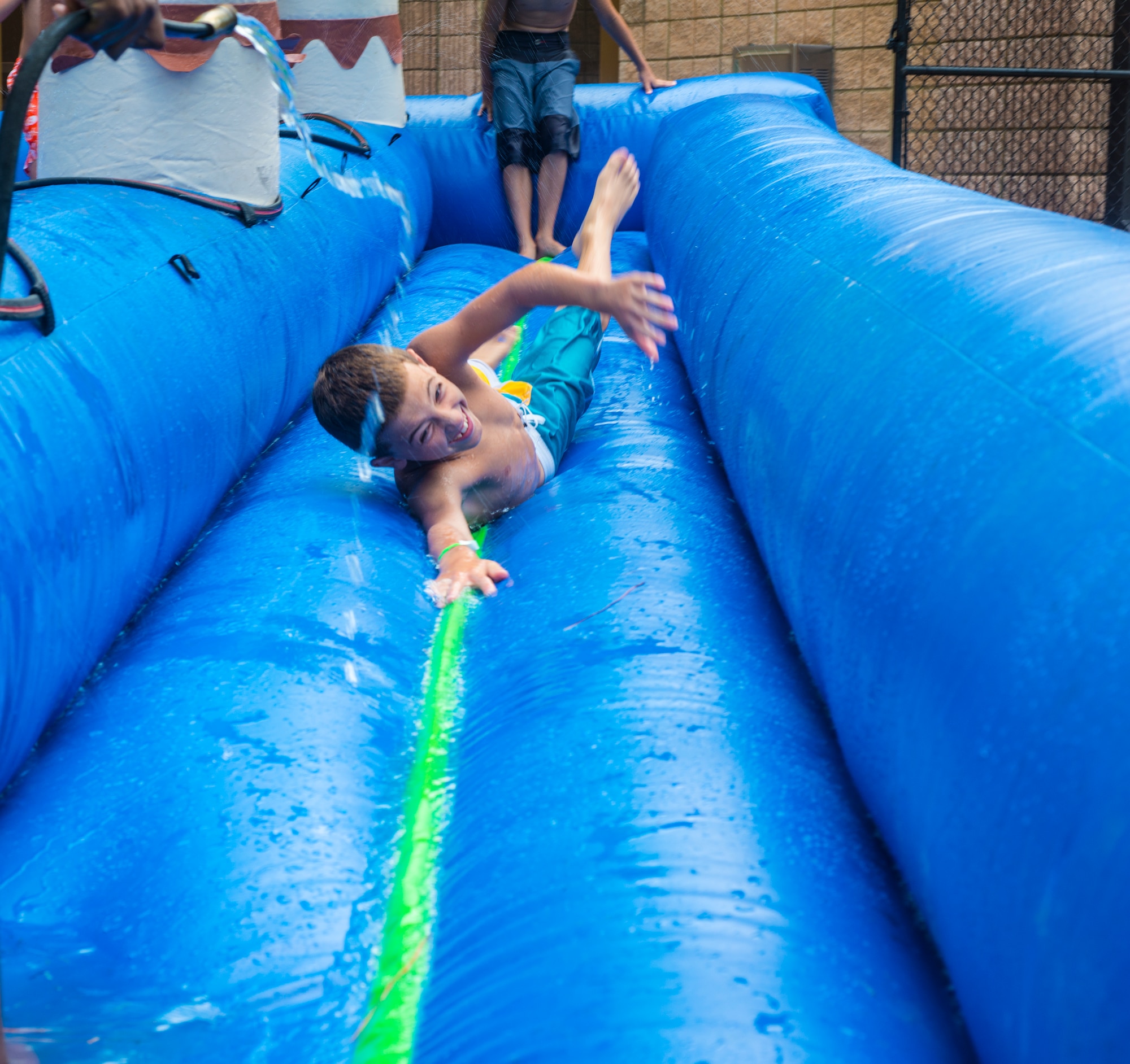 Logan White, son of U.S. Air Force Tech. Sgt. James White, 820th Combat Operations Squadron, heads down a water slide during the July Jamboree at Moody Air Force Base, Ga., July 22, 2014. The jamboree included various activities such as a watermelon eating and seed-spitting contest, karaoke battle, slip and slide bounce house, water balloon toss and hot potato. (U.S. Air Force photo by Airman 1st Ceaira Tinsley/Released) 