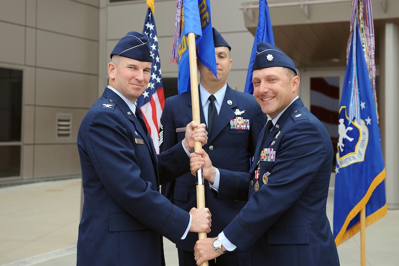 Col. Dennis Bythewood, 50th Operations Group commander, accepts the 2nd Space Operations Squadron guidon from Lt. Col. Thomas Ste. Marie during the squadron’s change of command ceremony July 2, 2014, at Schriever Air Force Base, Colo. Lt. Col. Todd Benson assumed command of the squadron. (U.S. Air Force photo/Dennis Rogers)