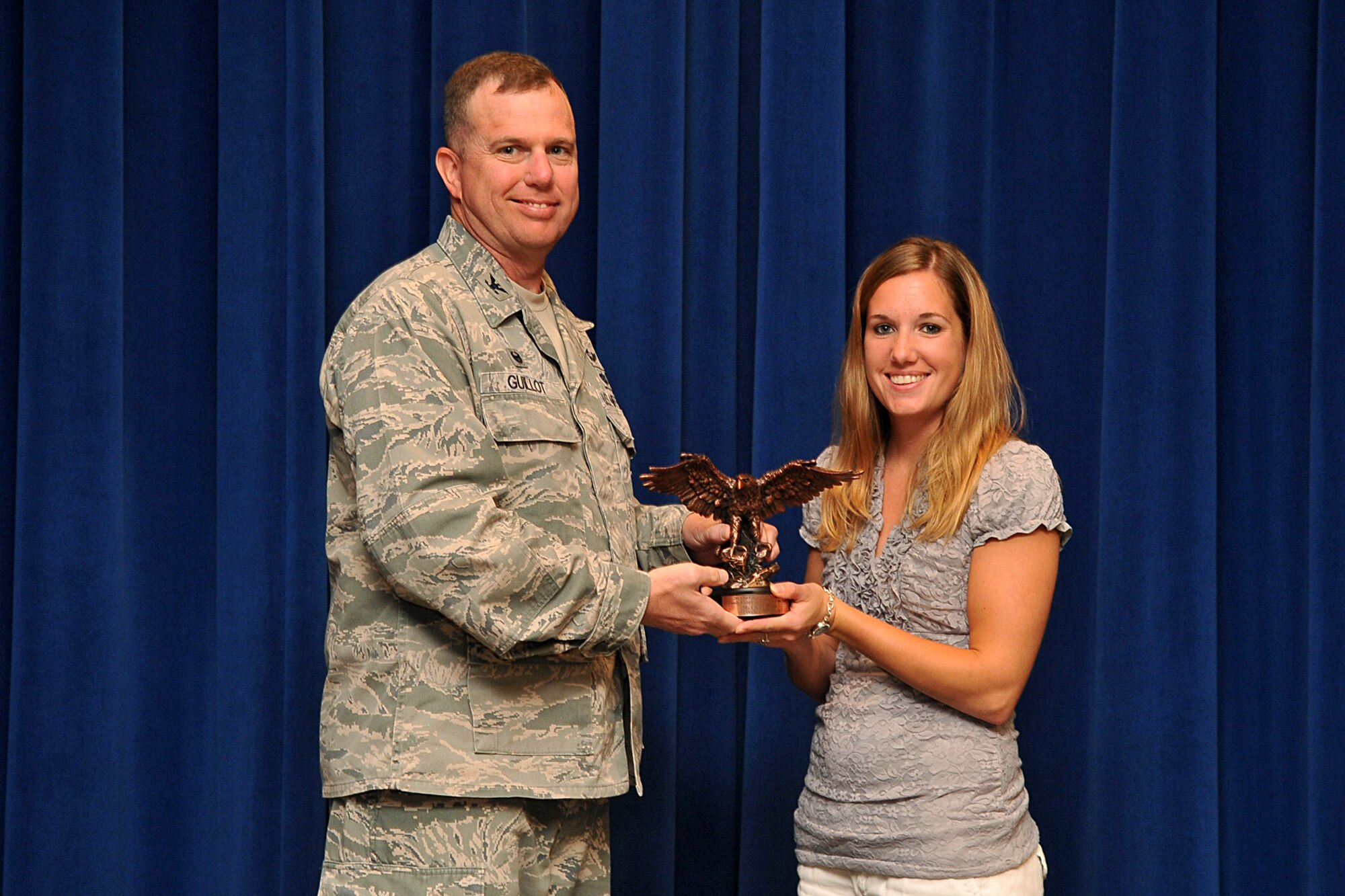 U.S. Air Force Colonel Gregory Guillot, 55th Wing commander, presents Erica Buum, wife of U.S. Air Force Staff Sgt. Anthony Buum, 55th Maintenance Group, with the 2013 Air Force Family Child Care Provider of the Year award July 21 during the weekly wing staff meeting at Offutt Air Force Base, Nebraska. She has provided child care on base since 2010 and during that time frame, has helped more than 80 families. (U.S. Air Force photo by Charles Haymond)