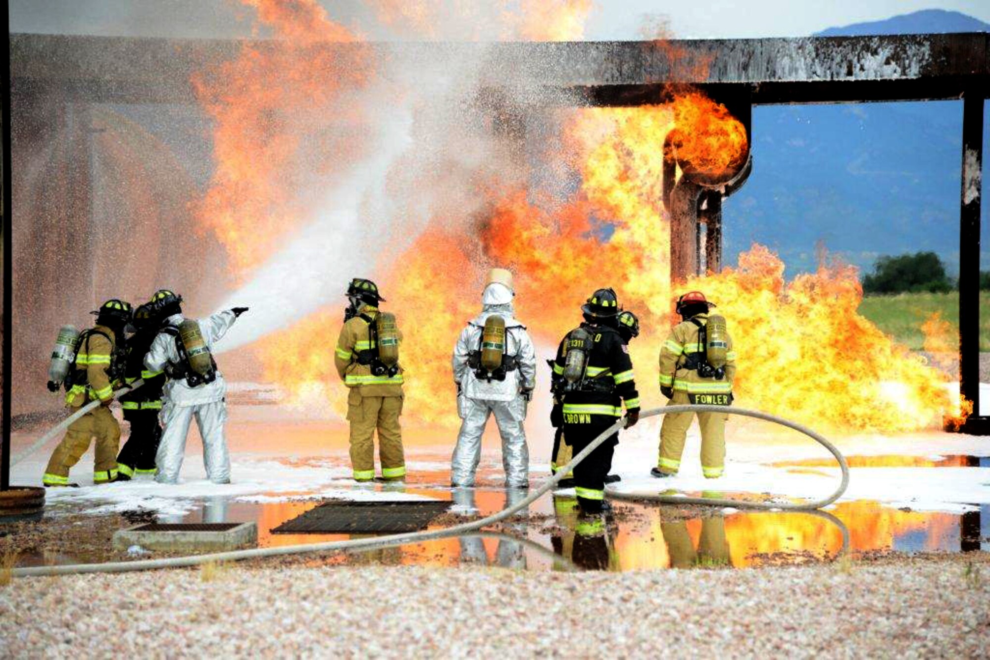 PETERSON AIR FORCE BASE, Colo. — Prepared to fight as a team, service members with the Peterson Air Force Base Fire Department (in tan and silver protection gear) conduct live training with the Cimarron Hills Fire Department (in black protective gear) at a special training facility on base. All firefighters in attendance had a chance to practice specialized tactics against a real fire. The all steel-training structure ‘fueled’ by a massive propane tank is designed to resemble a C-130 airframe and provides training for firefighters with a realistic scenario to learn and maintain their skills. (U.S. Air Force photo/Michael Golembesky)