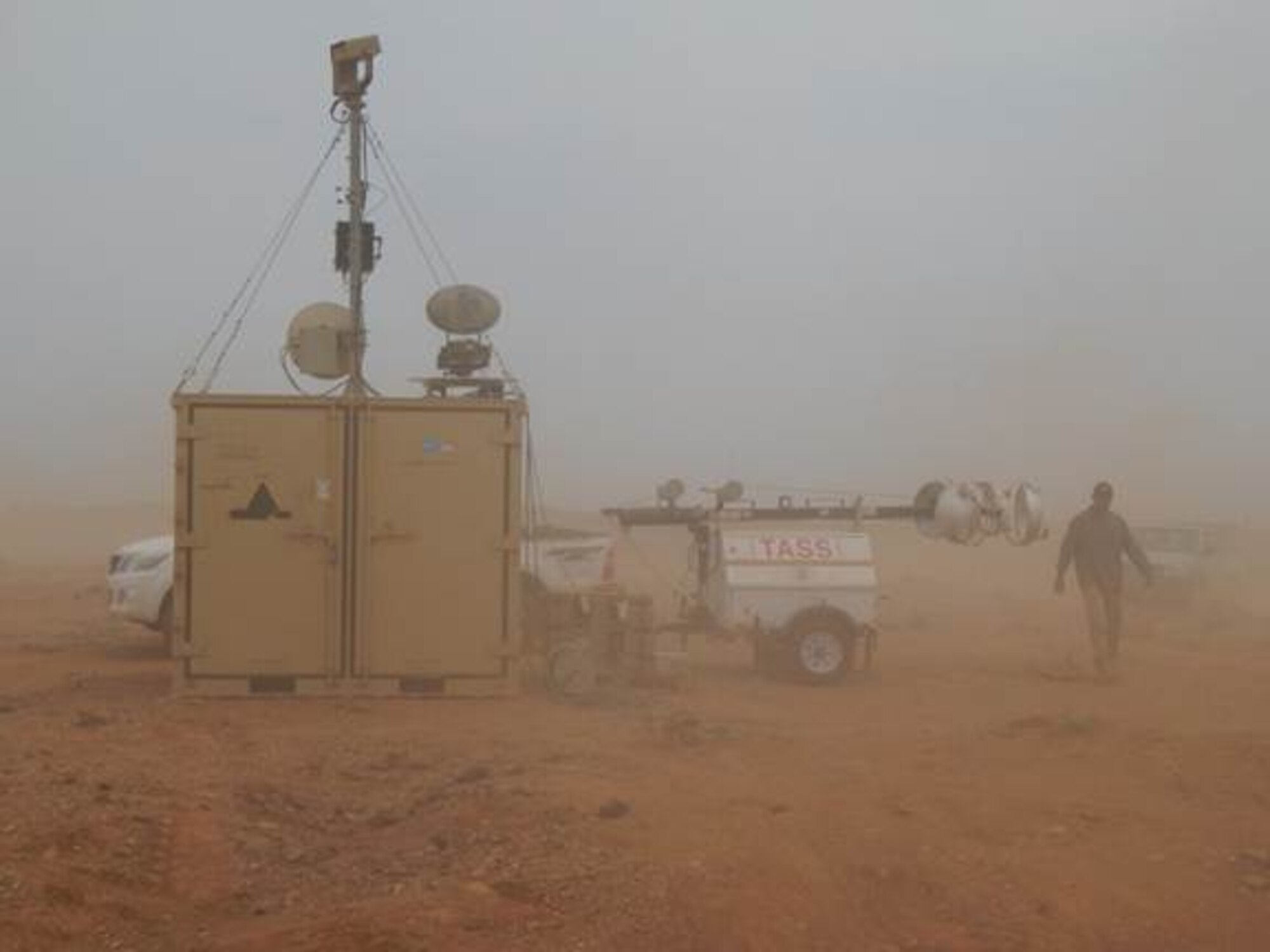 Installed TASS equipment provides surveillance, detection and situational awareness to the operating location during a sand storm. CONEX containers provide an excellent platform to mount equipment, provide more height for improved detection capability, and house other TASS components from the elements. Hanscom’s Force Protection Division, in collaboration with service partners and using rapid acquisition methods, recently completed the installation ahead of schedule and under budget. (Photo by Jimmy Waller)