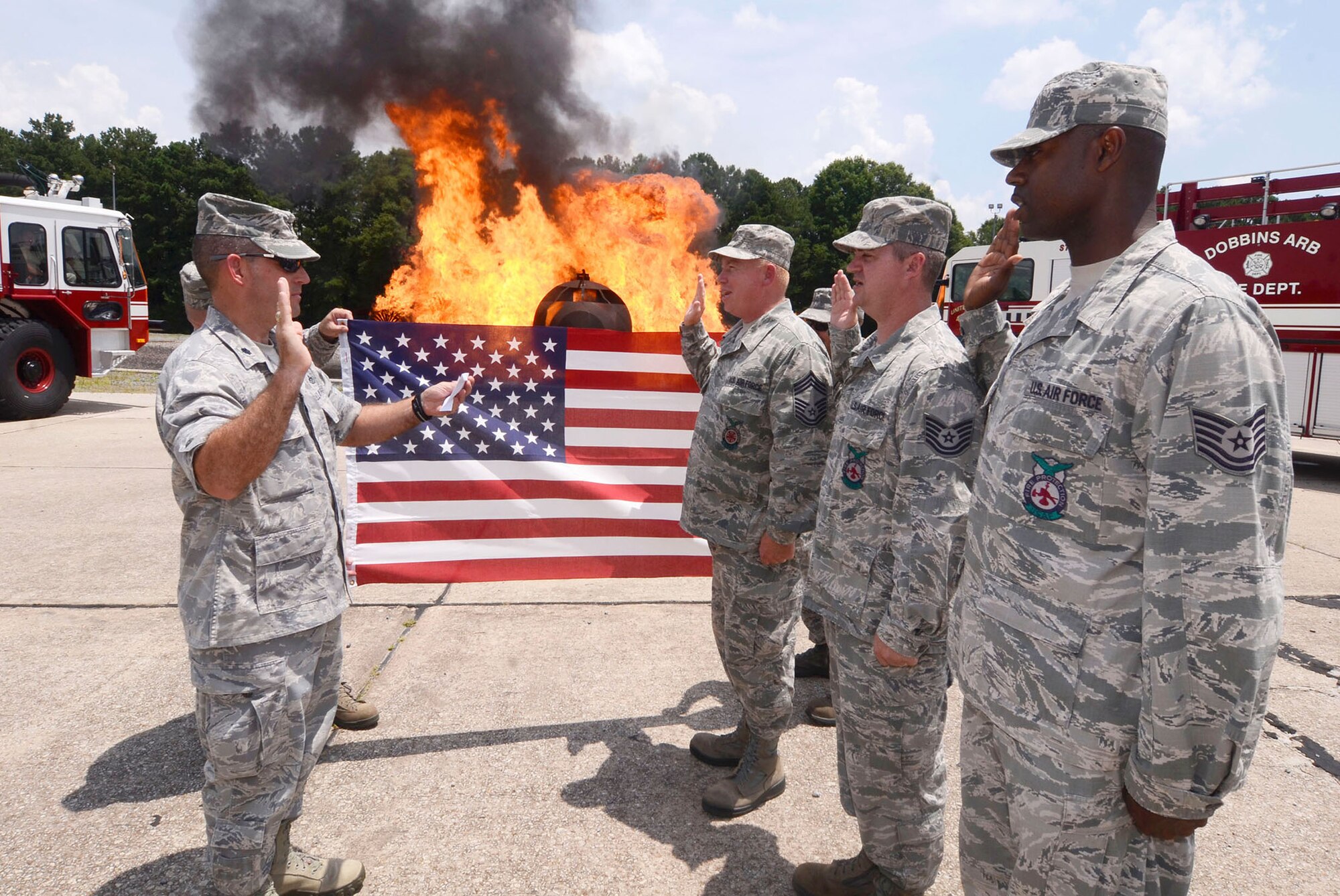 Chief Master Sgt. Zenith L. Parker, Tech. Sgt. Thomas Lane, (center) and Tech. Sgt. Quincy Davis from the 94th Civil Engineer Squadron Fire Department reenlist at the aircraft burn simulator, Dobbins Air Reserve Base, Ga. July 13, 2014. The oath was rendered by Lt. Col.  Scott A. Carlin, 94th Civil Engineer Squadron commander. (U.S. Air Force photo/Don Peek)