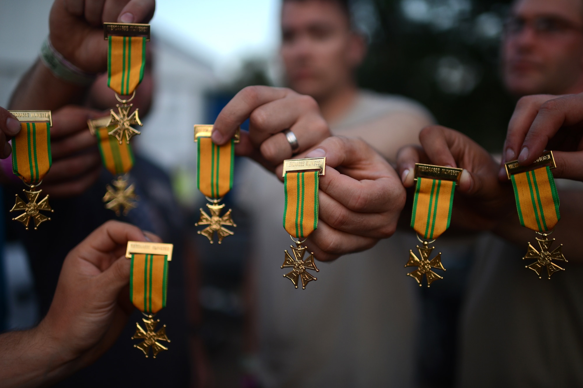 Finishers of the International Four Days Marches Nijmegen from the U.S. Army 361st Civil Affairs Brigade and U.S. Air Force 52nd Fighter Wing hold up their completion medals in Nijmegen, the Netherlands, July 18, 2014. Throughout the week, 39,910 civilians and military members from countries around the world completed the march to receive their medal. (U.S. Air Force photo by Senior Airman Gustavo Castillo/Released)