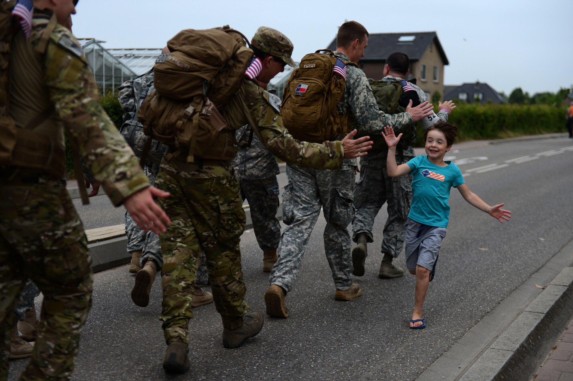 A child celebrates with International Four Days Marches Nijmegen participants from the U.S. Army 361st Civil Affairs Brigade and U.S. Air Force 52nd Fighter Wing before crossing a bridge in Nijmegen, Netherlands, July 15, 2014. Military participants gave out small souvenirs to on looking children cheering and celebrating throughout the march. (U.S. Air Force photo by Senior Airman Gustavo Castillo/Released)