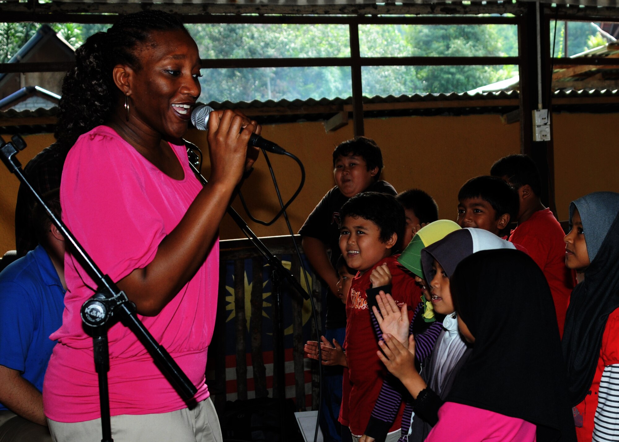 A member from the Air Force Band of the Pacific sings to the children at Pondok Penyayang Raudhah orphanage in Kuala Lumpur, Malaysia, during a community outreach visit June 14, 2014.  The 353rd Special Operations Group, alongside participants from Pacific Air Forces Exercise Cope Taufan 2014, came together to raise over $1,000 in supplies for the orphanage.  The two groups donated their time to help with small repairs and yard cleanup around the orphanage in addition to visiting with the children.  (U. S. Air Force photo by Tech. Sgt. Kristine Dreyer)
