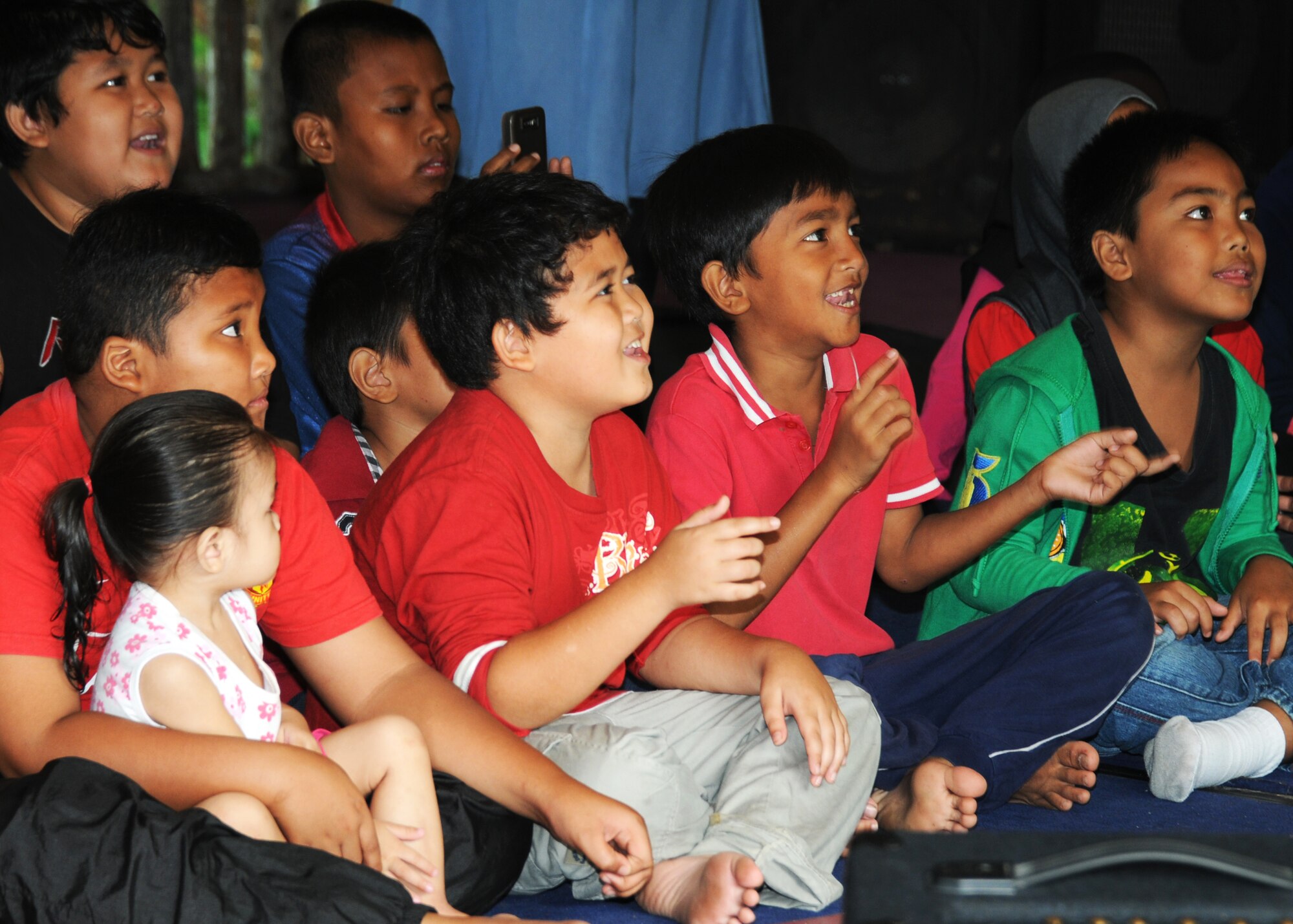Children from the Pondok Penyayang Raudhah orphanage in Kuala Lumpur, Malaysia, enjoy music provided by the Air Force Band of the Pacific June 14, 2014.  The 353rd Special Operations Group, alongside participants from Pacific Air Forces Exercise Cope Taufan 2014, came together to raise over $1,000 in supplies for the orphanage.  The two groups donated their time to help with small repairs and yard cleanup around the orphanage in addition to visiting with the children.  (U. S. Air Force photo by Tech. Sgt. Kristine Dreyer)