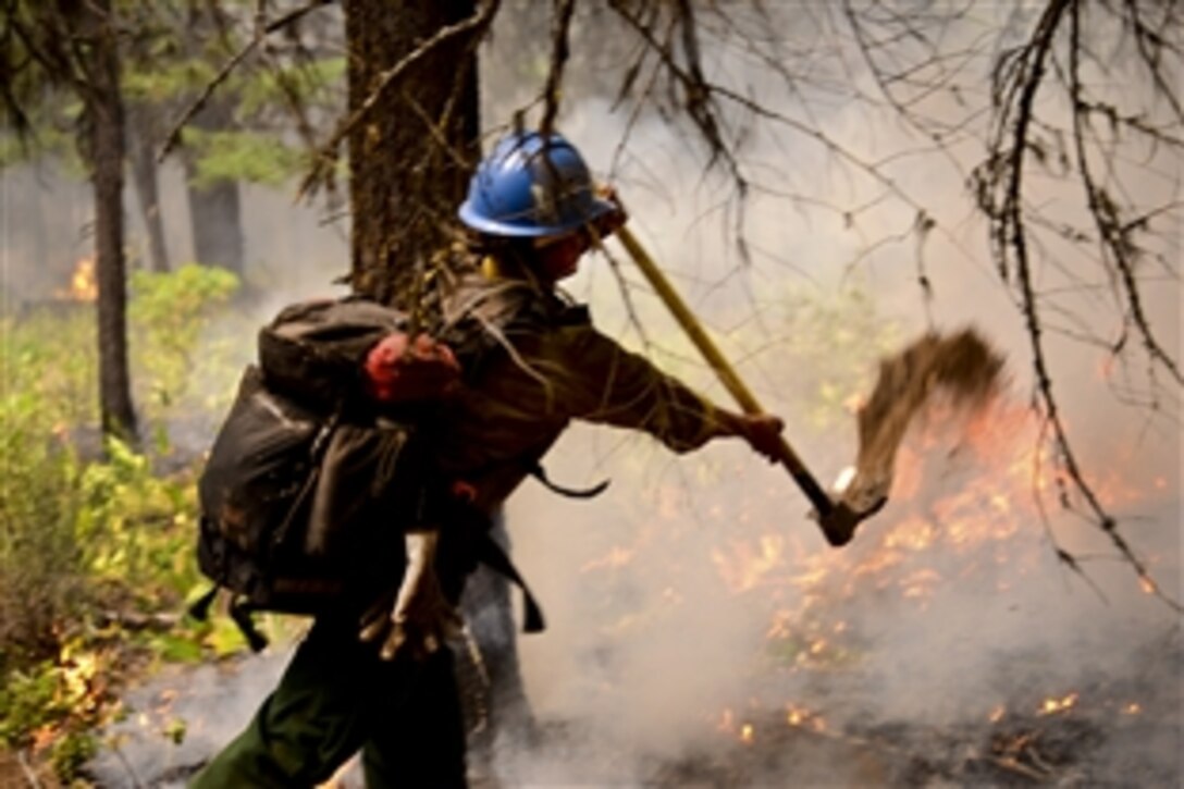 A firefighter with ground crews working to extinguish the Logging Unit fire west of Madras, Ore., July 21, 2014, spreads dirt over the base of trees to prevent the fire from destroying them. As part of the fire-suppression efforts, the Oregon Army National Guard has provided two CH-47 Chinook helicopters and two HH-60M Black Hawk helicopters to assist local authorities.