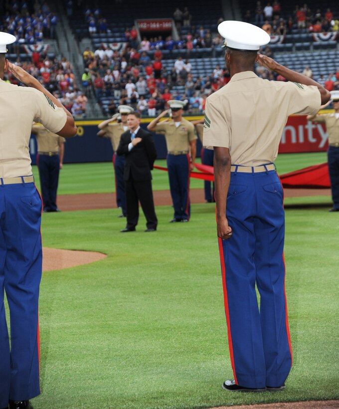 Marines, lining the bases, salute during the singing of the national anthem and presentation of colors during the Atlanta Braves’ Marine Corps Appreciation Day game, July 19 at Turner Field in Atlanta, Georgia.