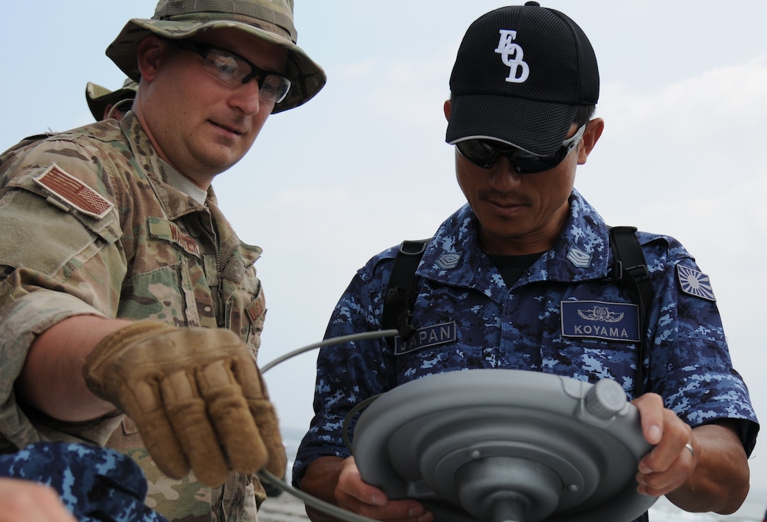 Staff Sgt. Justin Walter, right, explains to Japanese Maritime Self-Defense Forces Senior Petty Officer Akira Koyama where the fuse wiring on the explosive device goes July 15, 2014, at the Draughon Bombing Range, Misawa Air Base, Japan. The Japanese EOD members got to work hands-on with equipment used by U.S. military EOD forces. Walter is a 35th Civil Engineer Squadron EOD craftsman and Koyama is a Japanese EOD member. (U.S. Air Force photo/Senior Airman Jose L. Hernandez-Domitilo)