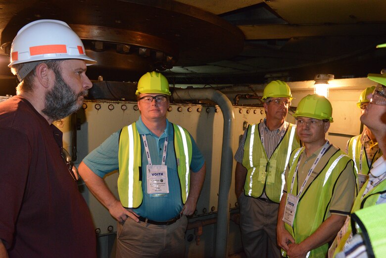 Paul Drinkard, Center Hill Dam power plant electrician, underneathe a generator explanins to a group of visitors how it works during a tour at the Center Hill Power plant on July 22, 2014.