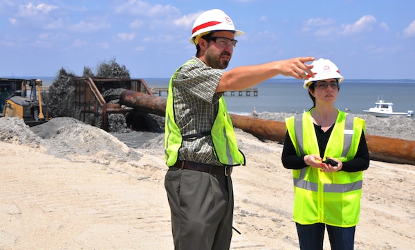 New York District Project Manager David Gentile points out an item to Project Analyst Catharine Russamano as a sand and water mixture pumps onto the beach in Port Monmouth, New Jersey, on July 1, 2014 as part of dune and beach construction activities. The dunes and beach are part of the first phase of a larger overall project designed to reduce coastal storm risks to the community. 