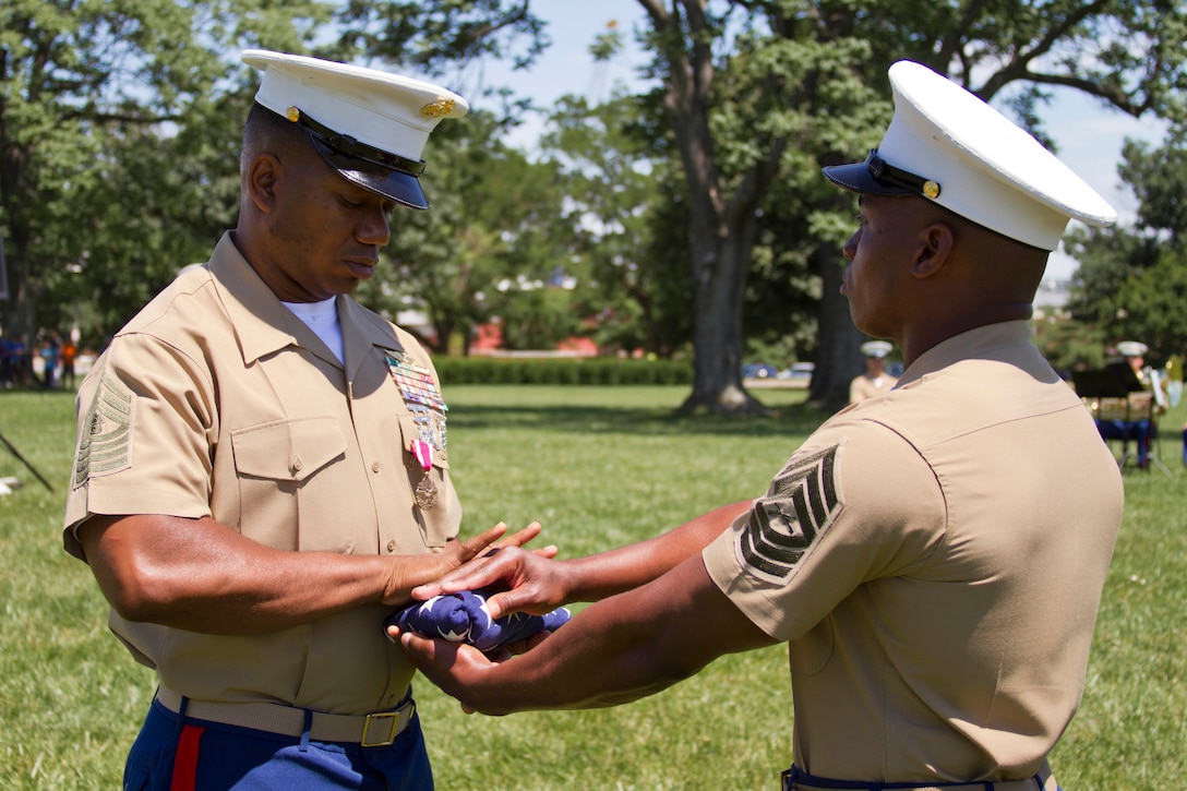 U.S. Marine Corps Master Gunnery Sgt. Richard W. Babb receives the American flag from Master Sgt. Dinky Z. Byers as part of his retirement ceremony at Fort McHenry in Baltimore, Md., June 20, 2014. The Trinidad native enlisted in the Marine Corps on August 1, 1984 and following recruit training went on to become a combat engineer. Babb deployed to the Mediterranean, North Africa, Japan, the Republic of Korea, Thailand, the South China Sea and participated in Operations Desert Shield and Desert Storm. He was also assigned to the Marine Corps Research and Development and Acquisition Command at Quantico, VA as a test operator of prototypes in the Emerging Technology and Mine/Counter-mine Warfare Systems section. In 1995, Babb reported for recruiting duty in Washington D.C. and has worked within the Marine Corps Recruiting Command for the past 18 years, serving in various positions such as canvassing recruiter, sub-station commander, assistant recruiter instructor and recruiter instructor. In September 2008, Babb was assigned to be the recruiter instructor for RS Baltimore, which would be his final duty station. Babb’s dedication to his duties directly influenced RS Baltimore’s success, earning them recognition by the Commandant of the Marine Corps as one of the superior recruiting stations in the nation for the years of 2008, 2009, 2011, and 2013. (U.S. Marine Corps photo by Sgt. Bryan Nygaard/Released)