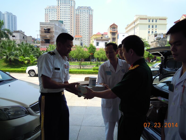 Army Maj. Jacky Ly, Office of Defense Cooperation chief from U.S. Embassy at Hanoi, (left) hands a box of burn cream to Lt. Col. Pham Xuan Chung, Director of Pharmacy for Vietnam Military Medical Department, and medical leadership at Vietnam Military National Institute of Burns July 23, 2014, at Hanoi, Vietnam.  (U.S. Air Force courtesy photo)