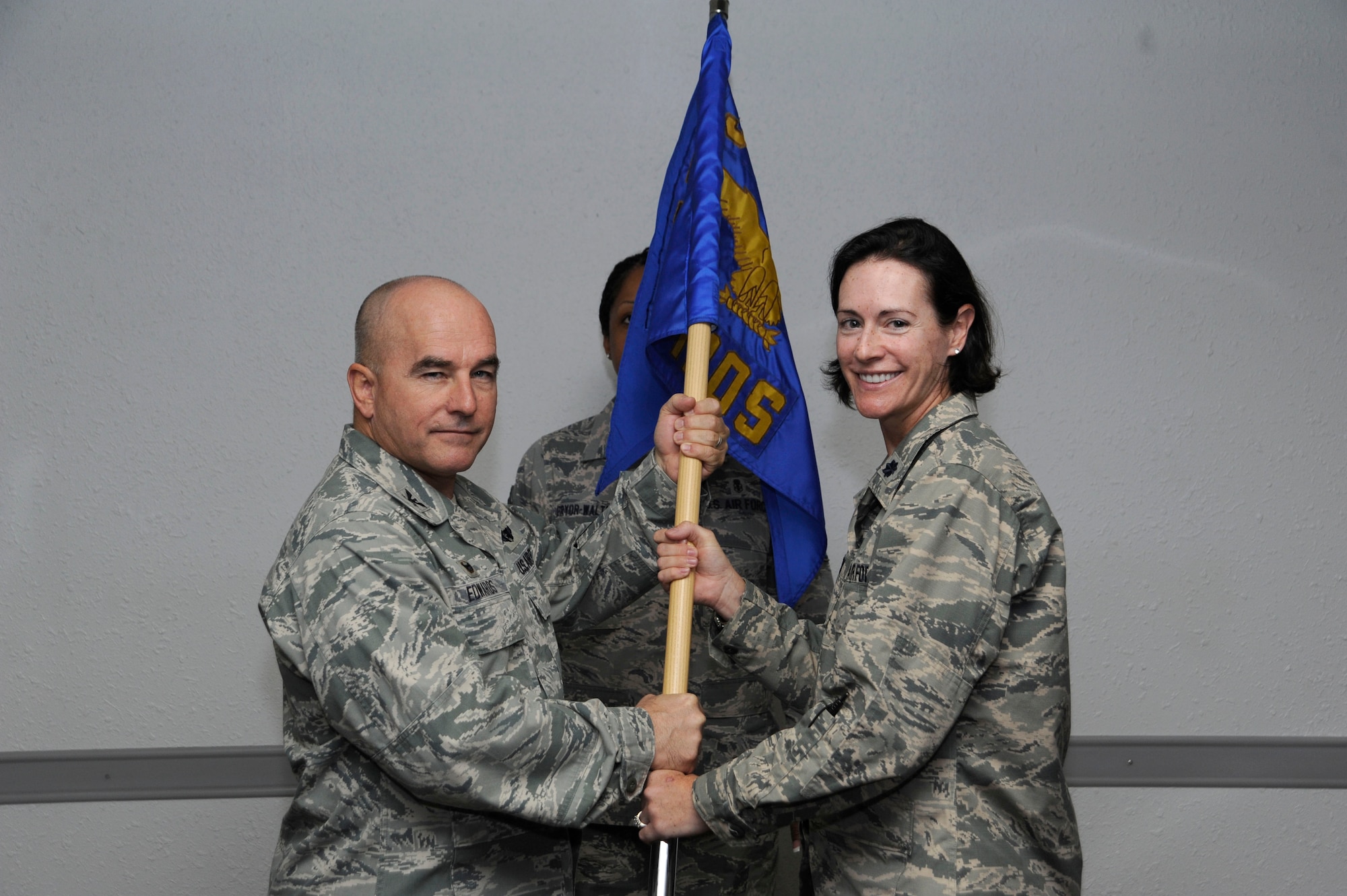 (Right to left) U.S. Air Force Lt. Col. Michelle Aaron accepts the guidon from Col. Bruce Edwards, 355th Medical Group commander at Davis-Monthan Air Force Base, Ariz., July 23, 2014. The passing of the guideon is a traditional military custom signifying the transfer of command, thereby signifying Aaron’s new role as the 355th Medical Operations Squadron commander. (U.S. Air Force photo by Airman 1st Class Betty R. Chevalier/Released)
