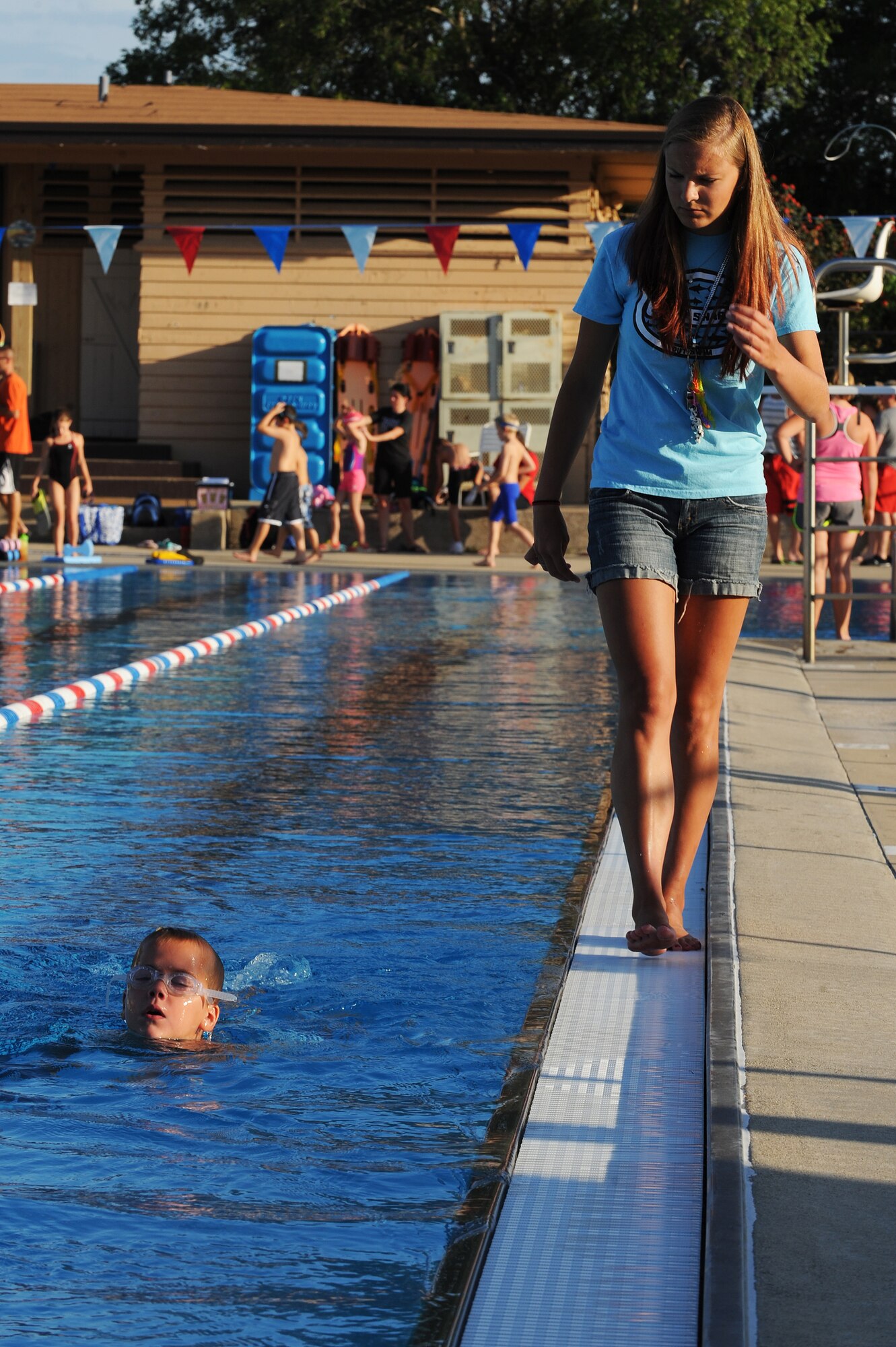 Brittany Wilda walks alongside Luke Litteken, making sure he isn’t flutter kicking when doing the breaststroke at Scott Air Force Base, Ill., July 16, 2014.  The breaststroke is swum in on the stomach, with both arms moving synchronously and executing short, half-circular movements underwater. The legs also move synchronously and execute a whip kick.   At a competition level, breaststroke swimmers will have to have endurance and strength to move quickly.  Wilda is a coach for the Scott Sharks.  (U.S. Air Force photo by Staff Sgt. Maria Bowman)