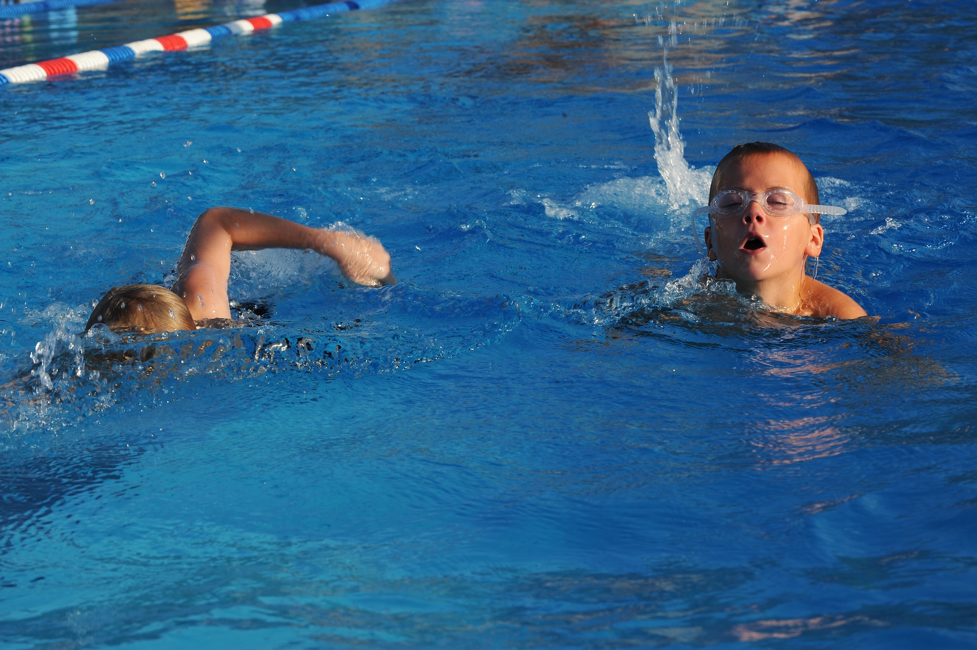 Jack Hodges and Luke Litteken work towards their goal of swimming 50 yards without stopping during the swim practice at Scott Air Force Base, Ill., July 16, 2014.  Swimmers are divided into three levels, depending on skill and ability.  Hodges and Litteken are in Level I, which is for beginners, and they swim for the Scott Sharks.  (U.S. Air Force photo by Staff Sgt. Maria Bowman)