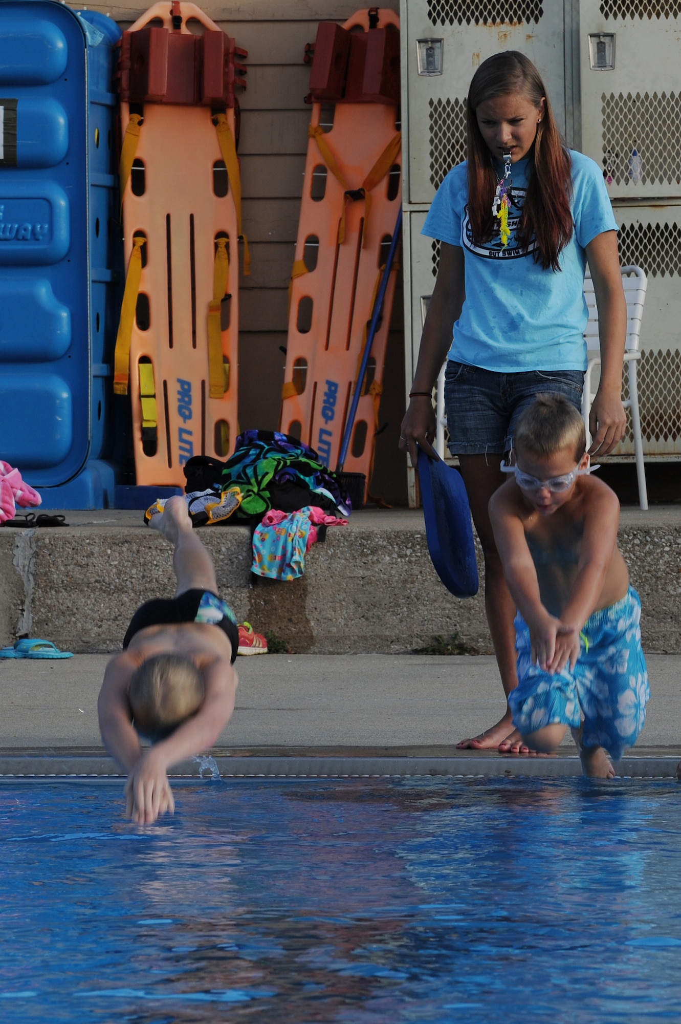 Brittany Wilda works with Jack Hodges and Luke Litteken, helping them with their dives at Scott Air Force Base, Ill., July 16, 2014.  During competitions, swimmers dive from starting blocks into the pool and begin the freestyle, butterfly stroke and the breaststroke.  When starting the backstroke, the swimmer starts in the water.  Perfecting the diving technique helps swimmers maximize their chances of winning.  Wilda is a coach for the Scott Sharks.  (U.S. Air Force photo by Staff Sgt. Maria Bowman)