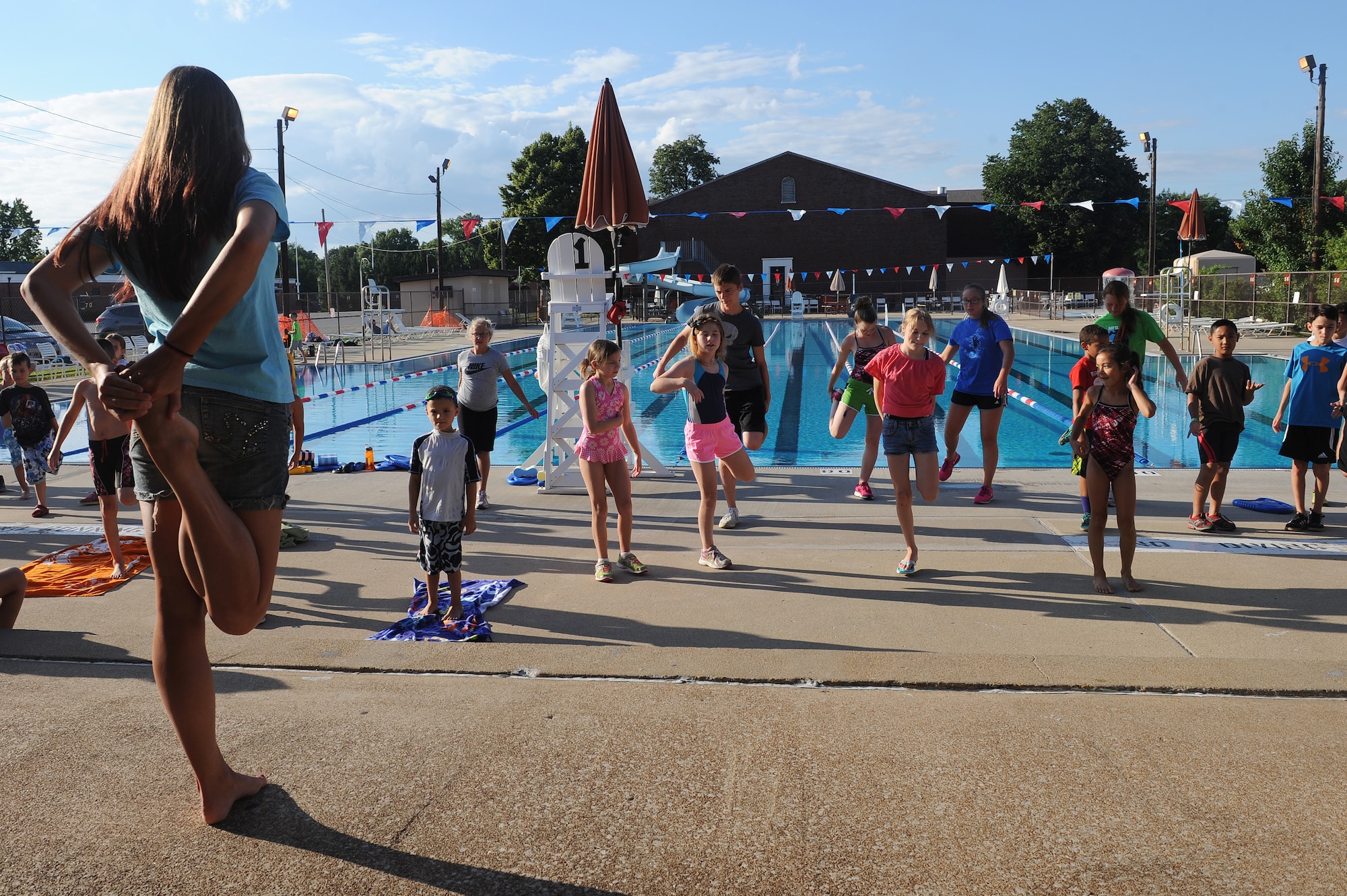 Brittany Wilda leads swimmers in stretching exercises before getting in the pool at Scott Air Force Base, Ill., July 16, 2014.  During swim practice, swimmers work on improving their freestyle, butterfly stroke, back stroke, and breast stroke.  Wilda is a coach for the Scott Sharks.  (U.S. Air Force photo by Staff Sgt. Maria Bowman)