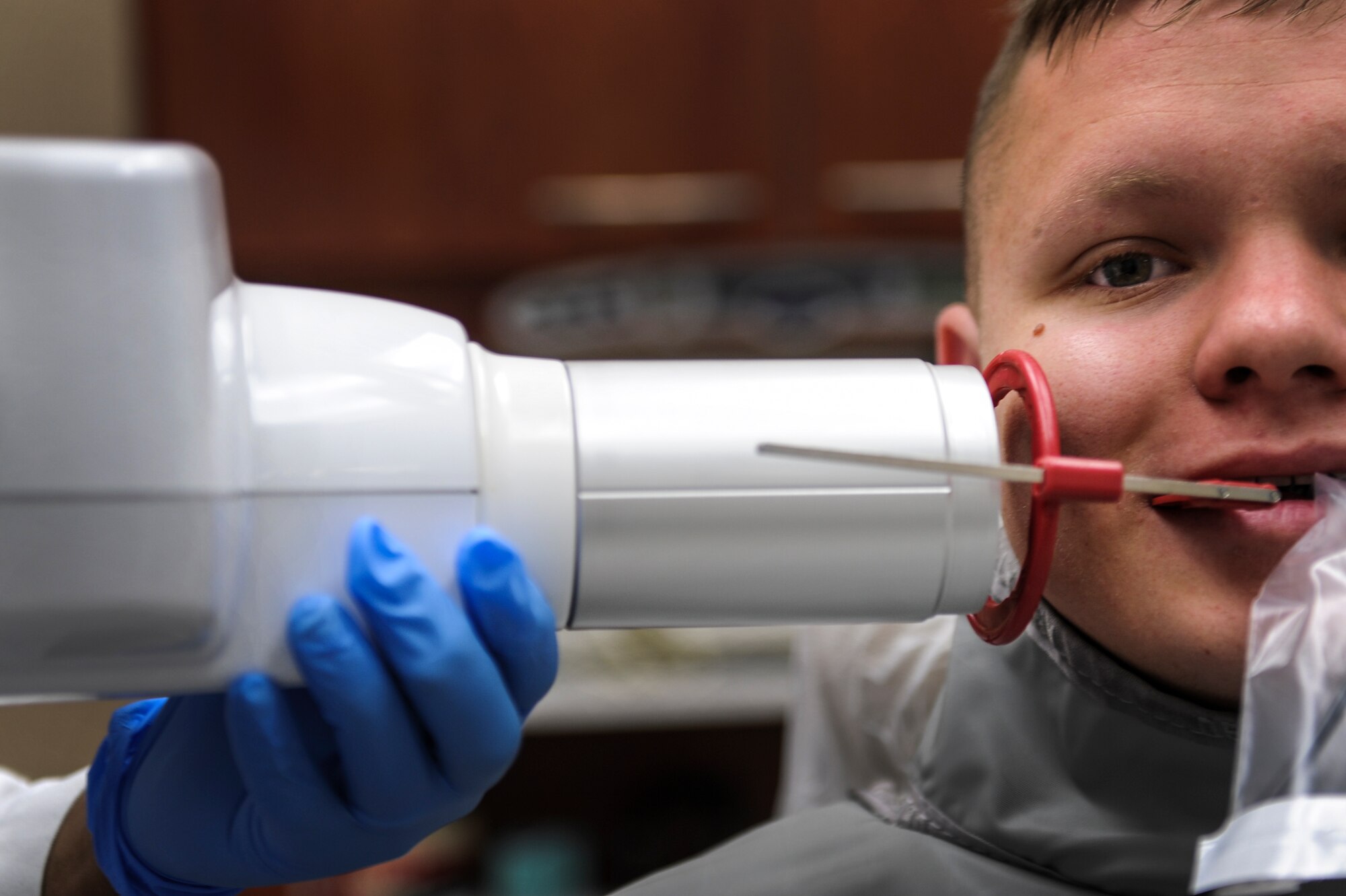 Airman 1st Class Jacob Burgener, a 53rd Airlift Squadron crew chief, bites down on a sensor, also known as a charged coupled device, holding it along the side of his gum line July 10, 2014, at Little Rock Air Force Base, Ark. The cable that is attached to the sensor runs to a computer on the other end displaying the images of the X-ray screen almost instantaneously.  (U.S. Air Force photo by Airman 1st Class Cliffton Dolezal)