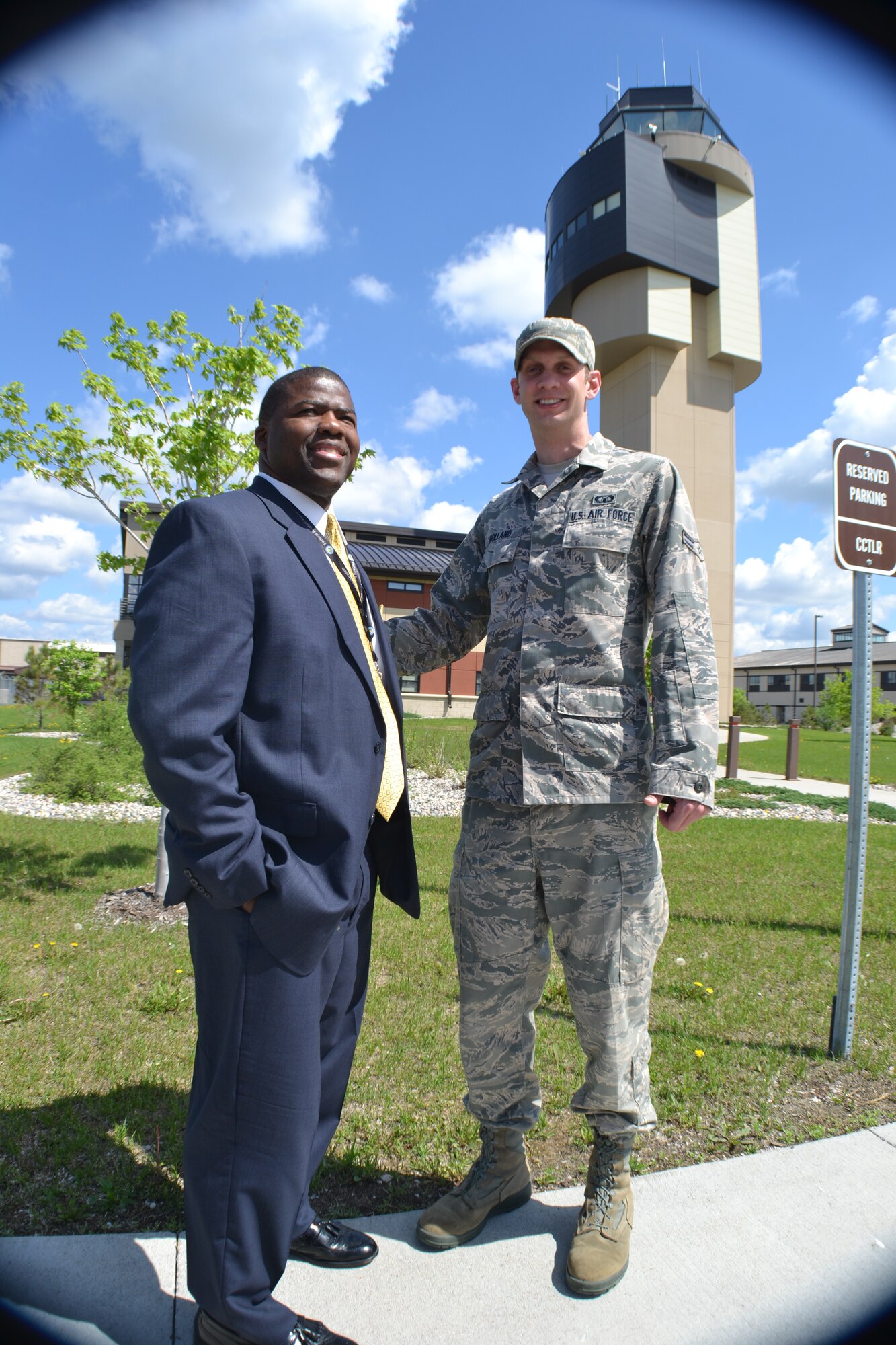 Federal Aviation Administration air traffic controller, Marvin Sutton, from the Air Route Traffic Control Center in Fort Worth, Texas, poses for a photo with 319th Operations Support Squadron air traffic controller, Airman 1st Class Steven Holland, in front of the air traffic control tower at Grand Forks Air Forks Air Force Base, N.D., on June 3, 2014. Holland served as the official escort for Sutton’s visit to his first duty stationed. Among several things, Sutton spoke about the differences he noticed when he transitioned from being Air Force air traffic controller to a civilian one in 1988 and about the valuable lessons he learned serving in the military. (U.S. Air Force photo/Staff Sgt. Luis Loza Gutierrez)