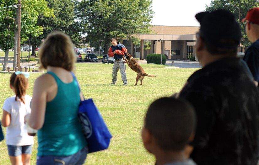 Digi, a military working dog from the 11th Wing Security Support Squadron, demonstrates his ability to incapacitate people on command at the library at Joint Base Andrews, Md., July 23, 2014.  Staff Sgt. Staff Sgt. Lucas Tripp, an 11th SSPTS MWD trainer, donned a protective training suit and refused to cooperate with an MWD handler during the demonstration.  The library hosted the MWD demonstration as part of its "Paws to Read" summer reading program, which runs through Aug. 9. (U.S. Air Force photo/Staff Sgt. Torey Griffith)