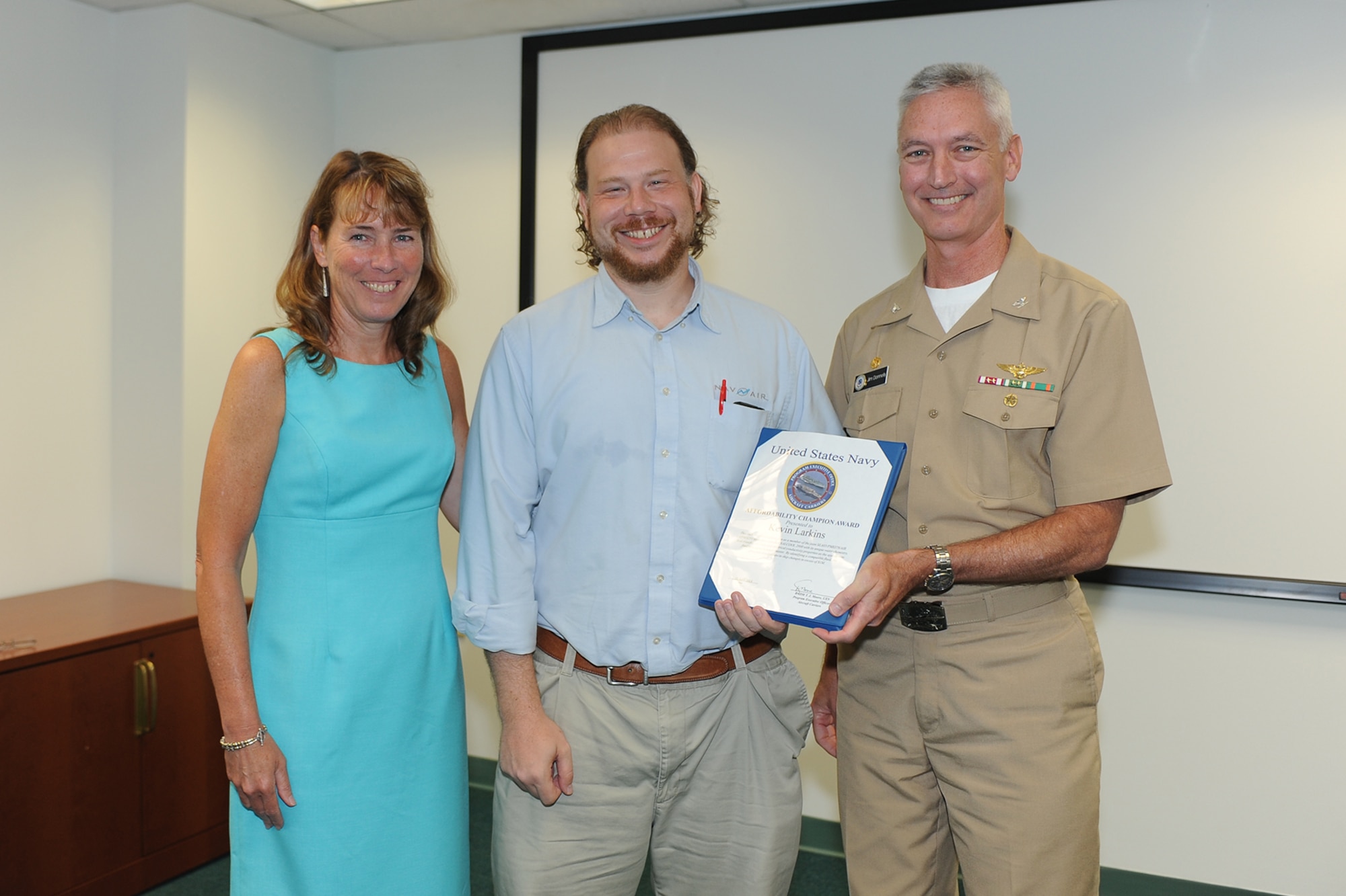 Kevin Larkins, center, the lead engineer for the AAG Water Twister Integrated Product Team, receives the Affordability Championship Award from Capt. James Donnelly, program manager for the Aircraft Launch and Recovery Equipment Program Office (PMA-251), and Kathleen Donnelly, director for the Support Equipment and Aircraft Launch and Recovery Equipment Department, on July 23, 2014, at Joint Base McGuire-Dix-Lakehurst. (U.S. Navy courtesy photo/Released)