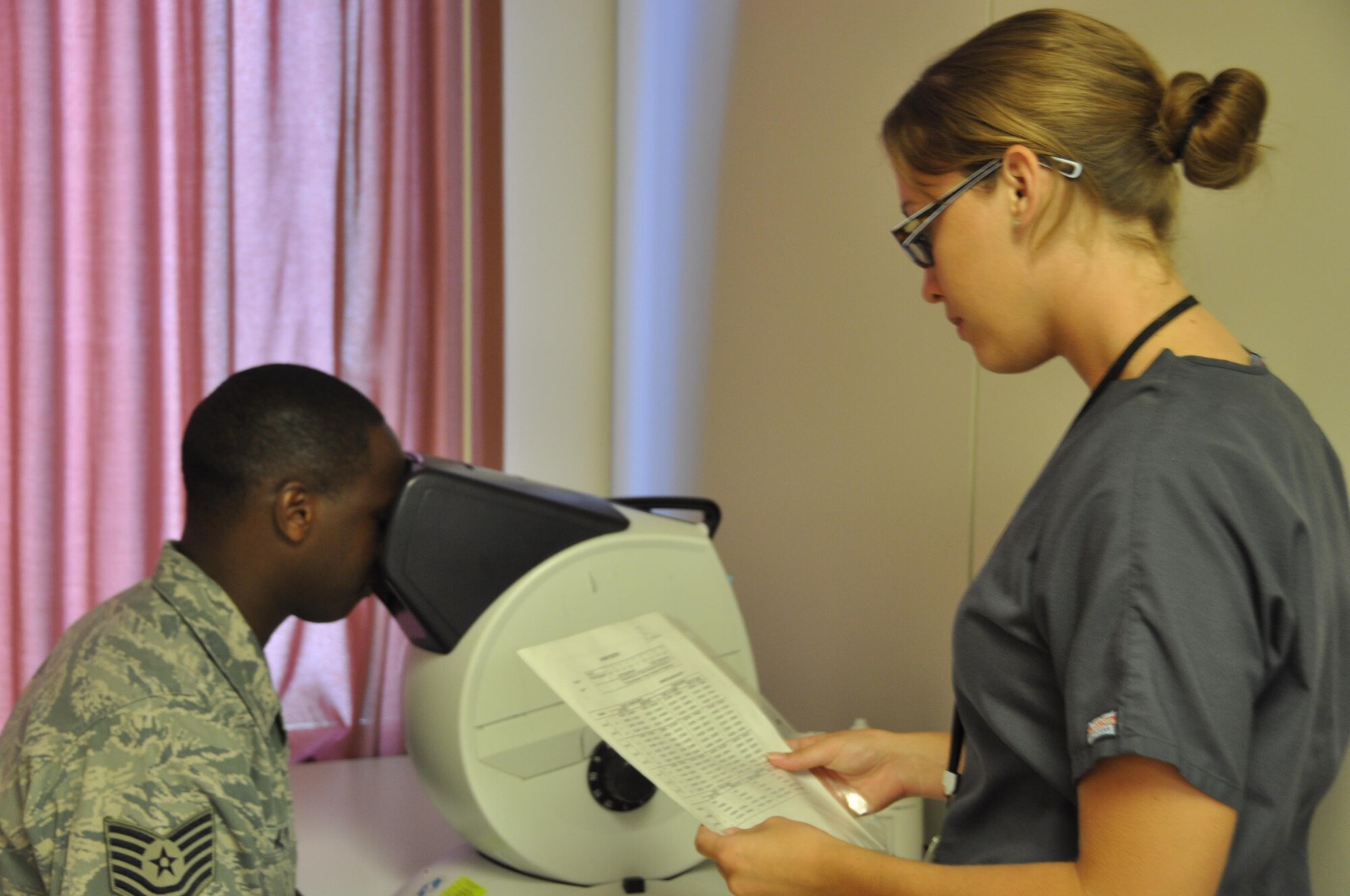 Katelyn Hooey, PHA cell technician, performs an eye test at the Travis Air Force Base David Grant USAF Medical Center July 14. The eye test is part of the preventative health assessment. (U.S. Air Force photo/Airman 1st Class Amber Carter)