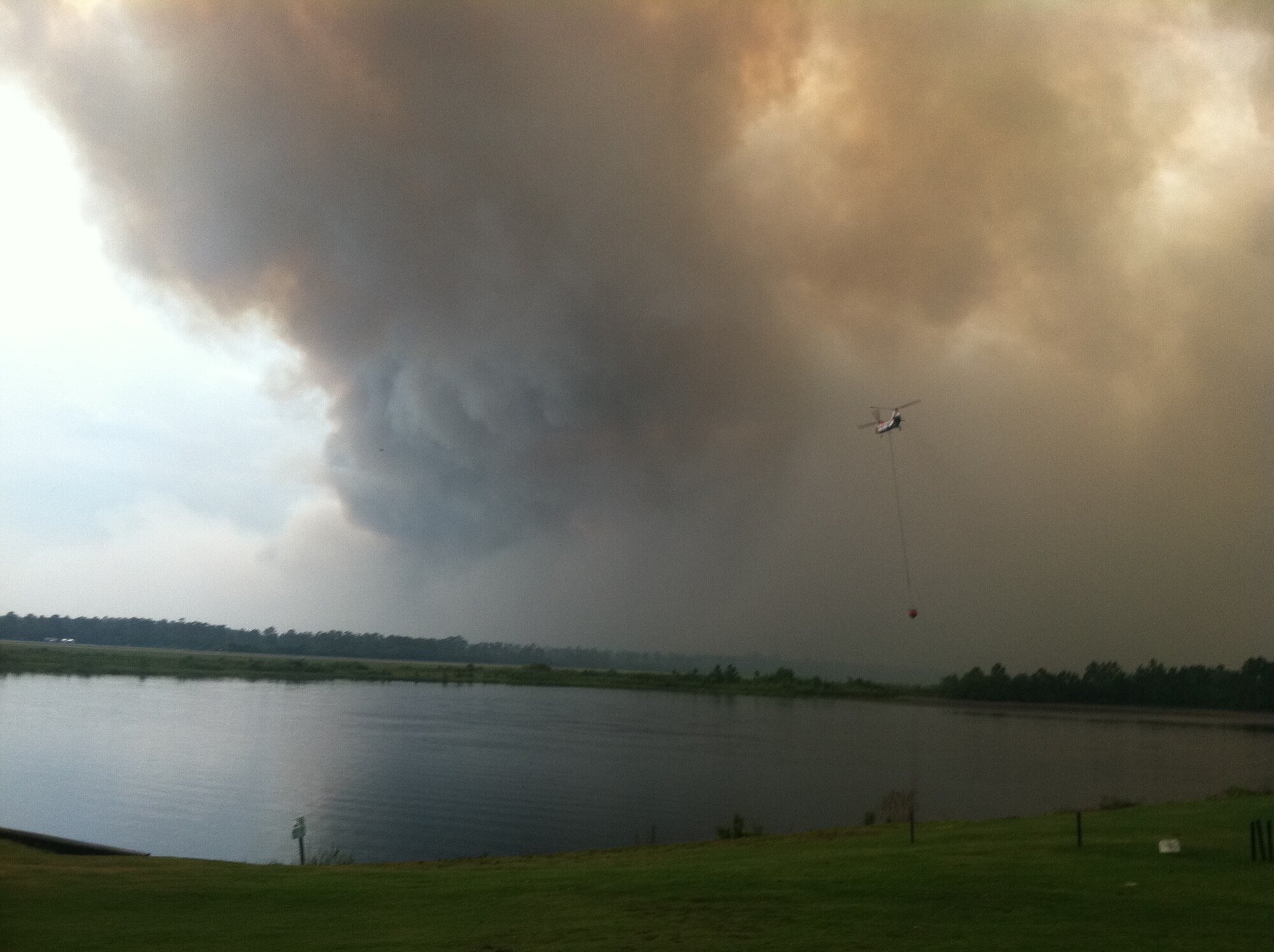 A Type 1 helicopter carries 2,000 gallons of water to a wildfire at Hurlburt Field, Fla. The "runway" fire burned nearly 3,000 acres, but didn't result in any lost structures or other Air Force assets. Each year, more than 1,000 wildland fires occur on Air Force property. The Wildland Fire Center, part of the Air Force Civil Engineer Center, was established to help Air Force installations manage wildland fire risk. (Courtesy Photo)