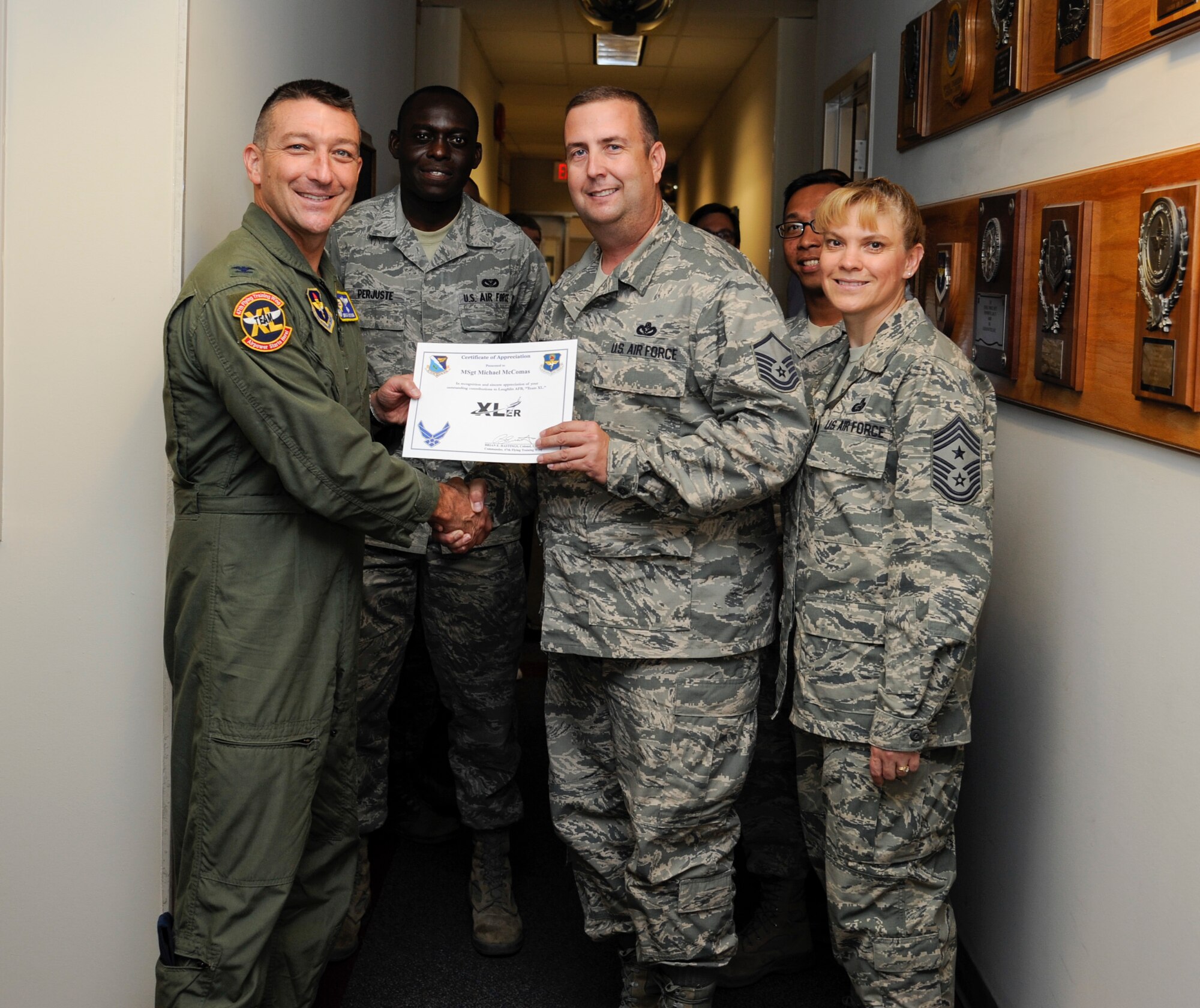 Master Sgt. Michael McComas, center, 47th Civil Engineer Squadron Engineering Flight superintendent, poses with Col. Brian Hastings, left, 47th Flying Training Wing commander, and Chief Master Sgt. Teresa Clapper, right, 47th FTW command chief, after being presented the XLer of the week award here July 23, 2014. The XLer is a weekly award chosen by wing leadership and given to those who consistently make outstanding contributions to their unit and Laughlin. (U.S. Air Force photo by Airman 1st Class Jimmie D. Pike)(Released)
