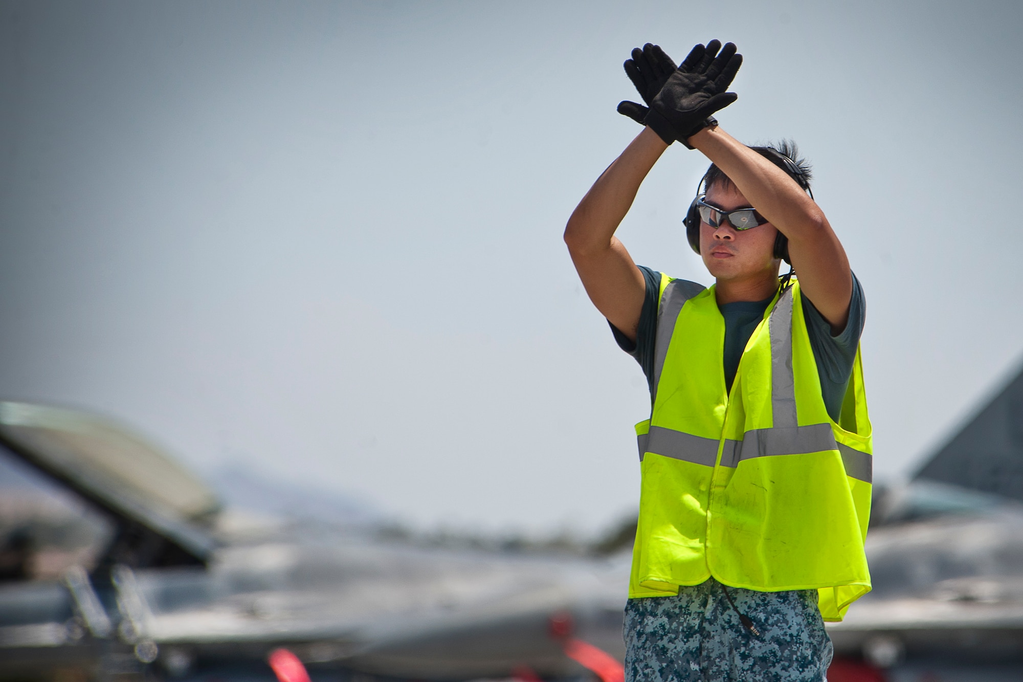 Republic of Singapore air force crew chief assigned to the 366th Fighter Wing, 428th Fighter Squadron, Mountain Home Air Force Base, Idaho, prepares to marshal an F-15SG aircraft during Red Flag 14-3, July 18, 2014 at Nellis AFB, Nev.  Red Flag provides maintenance support members from various airframes, military services and allied countries an opportunity to integrate and practice combat operations. (U.S. Air Force photo by Lawrence Crespo)
