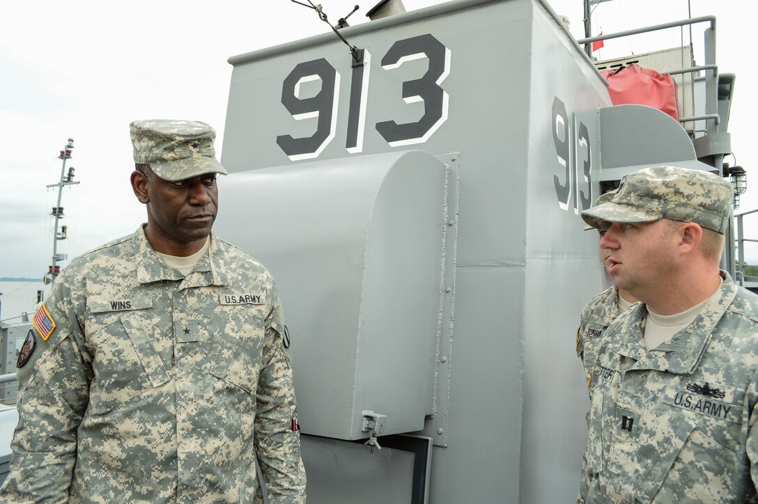 U. S. Army Brig. Gen. Cedric T. Wins,  Army Capabilities Integration Center, capabilities director,  listens to Capt. Keith Fetter, 73rd Transportation Company (Floating Craft), 10th Transportation Battalion, 7th Transportation Brigade (Expeditionary) commander, during a tour at 3rd Port at Fort Eustis, Va., July 21, 2014.  Wins visited with vessel masters of various water crafts and toured vessels while at 3rd Port. (U.S. Army photo by Spc. Marian Alleva/Released)