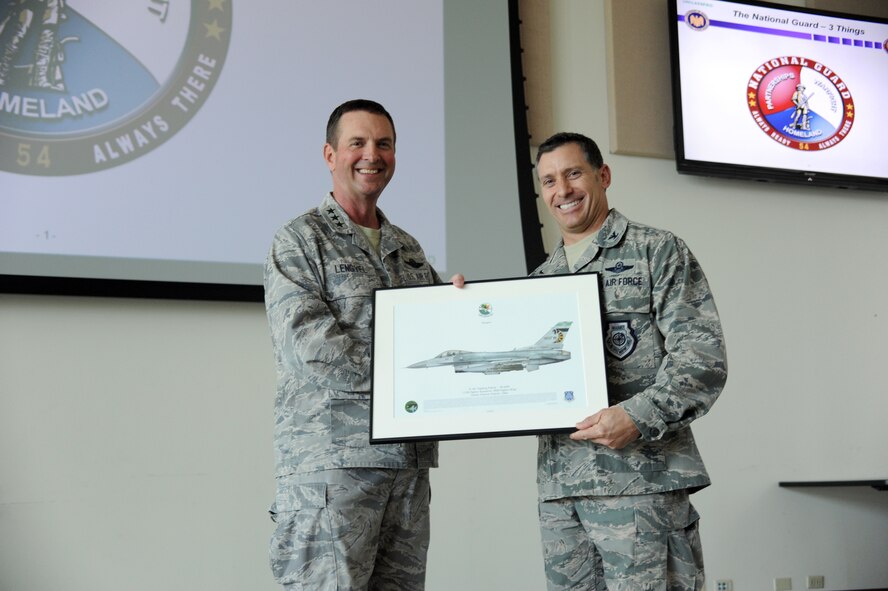 Col. Craig Baker, 180th Fighter Wing Commander, presents the Vice Chief of the National Guard Bureau, Lt. Gen. Joseph Lengyel, with a lithograph from the wing during Lengyel’s visit to the Ohio-based Air National Guard unit July 17, 2014. While visiting the Ohio-based Air National Guard unit, Lengyel received an up-close look at the wing’s best programs from green energy, Defense Support to Civil Authorities and the wing’s top performing Aerospace Control Alert mission. (Air National Guard Photo by Staff Sgt. Amber Williams/Released).