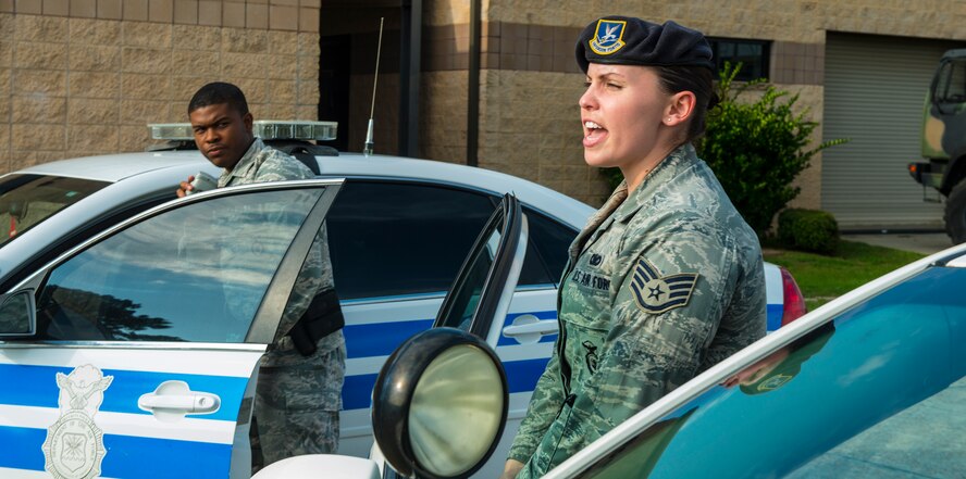 U.S. Air Force Airman 1st Class Levar Weston, left, radios in to the control center while Staff Sgt Amy Carpenter, 23d Security Forces Squadron patrolman, talks a suspect out of a vehicle during a simulated training exercise at Moody Air Force Base, Ga., July 22, 2014. The exercise simulated a high-risk person illegally gaining access to the base.  (U.S. Air Force photo by Airman 1st Class Ceaira Tinsley/Released)