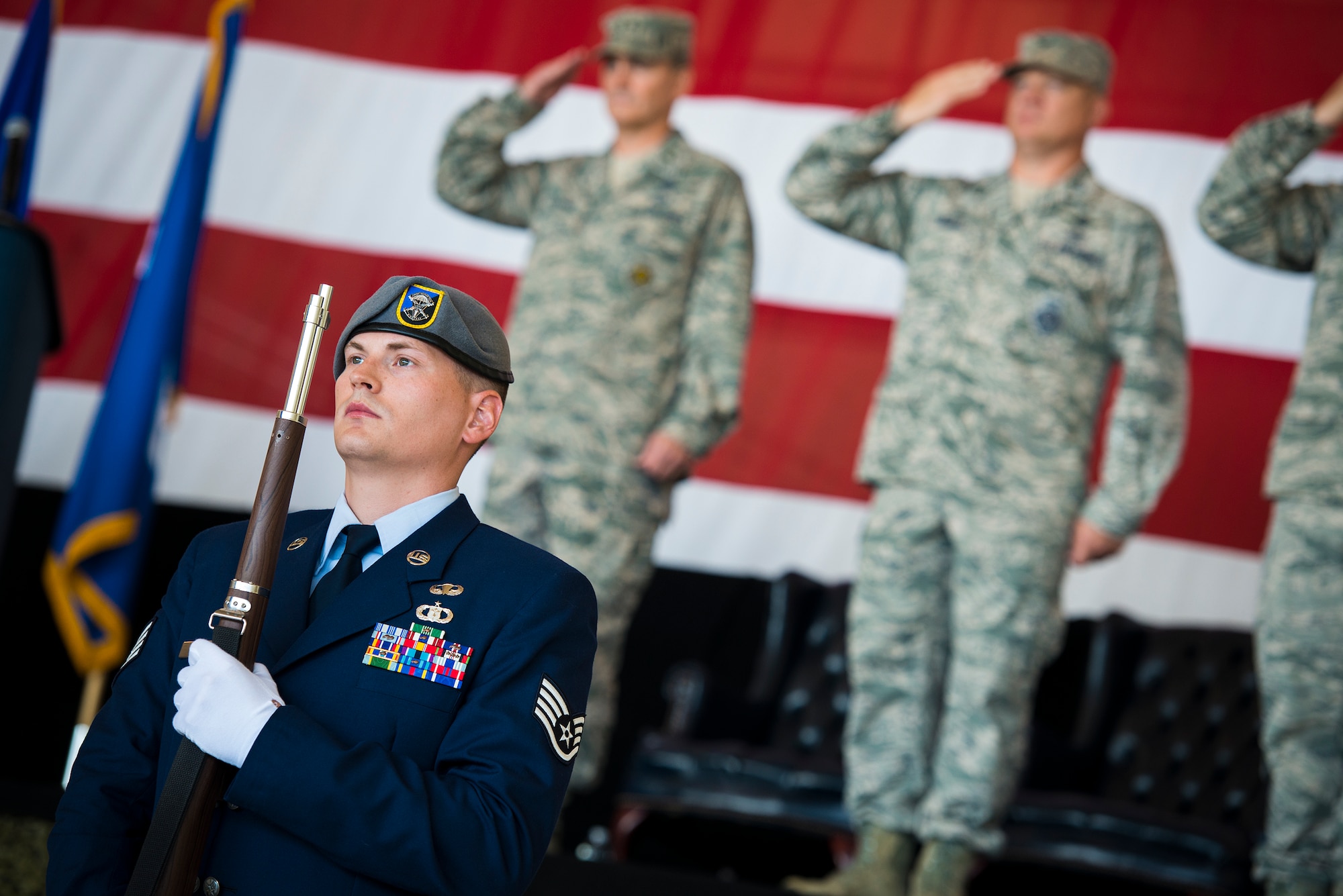 U.S. Air Force Staff Sgt. Bryant Lamay, 18th Weather Squadron airborne weather forecaster, symbolically protects the flag during the presentation of the colors as part of a change of command ceremony at Moody Air Force Base, Ga., July 23, 2014. A traditional change of command ceremony begins with an honor guard detail presenting the colors and the singing of the National Anthem. (U.S. Air Force photo by Airman 1st Class Ryan Callaghan/Released)