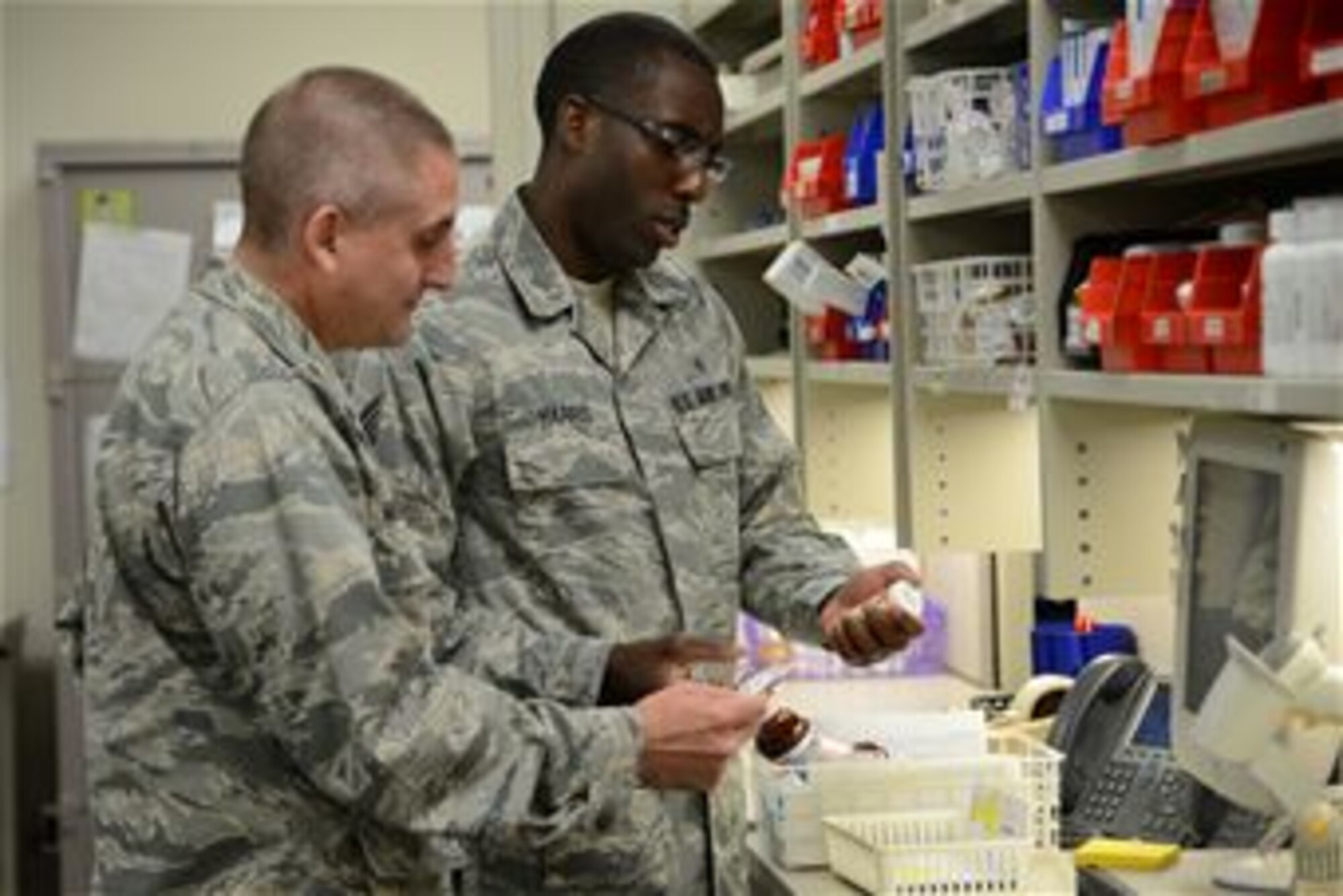 U.S. Air Force Reserve Staff Sgt. Jermaine Harris, 445th Aerospace Staging Squadron pharmacy technician, inquires about a patient’s medication dosage with Maj. Charles Miller, 44th ASTS pharmacist, during their tour of USAF Hospital Langley at Langley Air Force Base, Va., July 21, 2014. Miller said his three biggest priorities behind the counter are to ensure patients get the correct medication, the dosages are accurate and the medication is handled with the utmost safety. The Reservists completed their required biannual training for their career-specific duties to ensure they are prepared to deploy if called upon. (U.S. Air Force photo by Airman 1st Class Devin Scott Michaels/Released)