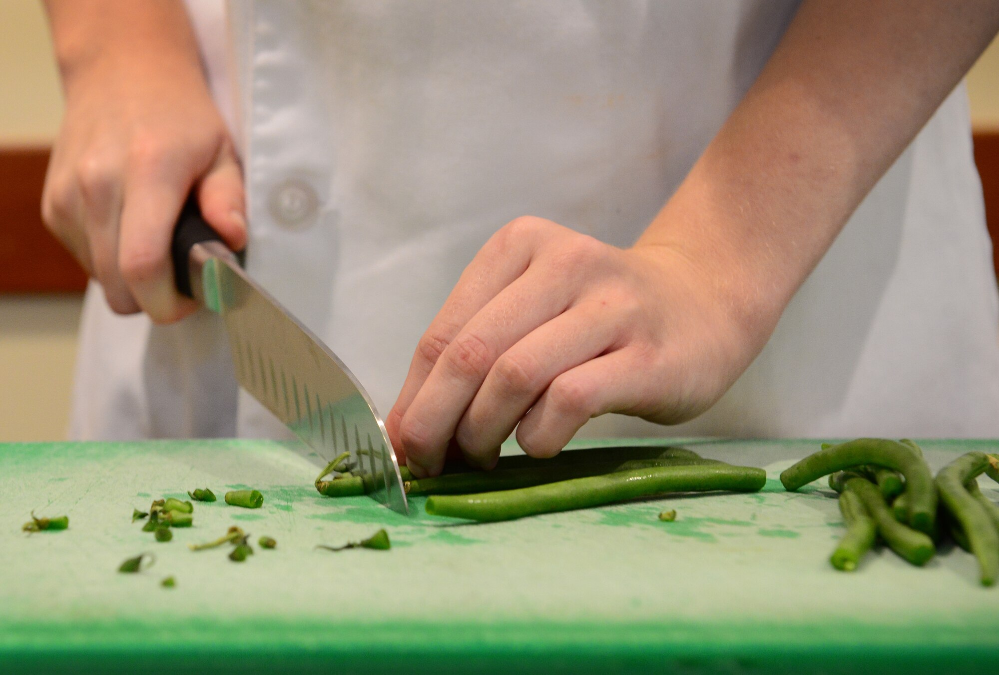 Airman 1st Class Angela Berg, 31st Force Support Squadron food services journeyman, cuts green beans during a cooking class, July 24, 2014, at Aviano Air Base, Italy. Berg hosted the event to teach Aviano Airmen living in the dormitories, how to prepare a meal with the resources available to them. (U.S. Air Force photo/Senior Airman Matthew Lotz)