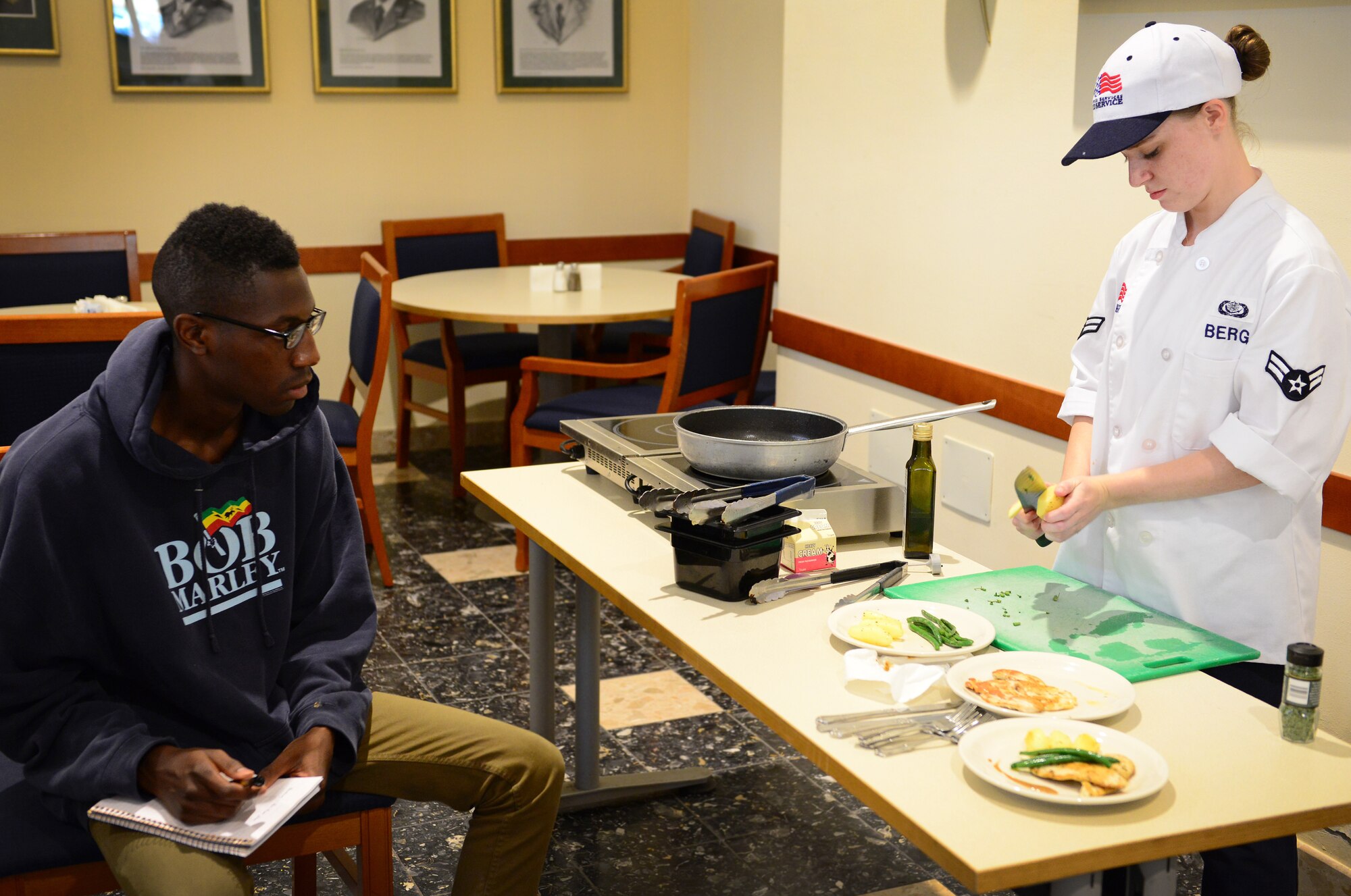 Airman 1st Class Angela Berg, 31st Force Support Squadron food services journeyman, teaches Airman 1st Class Jawanza Lynch, Aviano dorm resident, how to cut a potato during a cooking class she hosted, July 24, 2014, at Aviano Air Base, Italy. With the help of Berg, the students learned how to cook pan-seared chicken covered in a pan sauce with a side of sautéed potatoes and green beans. (U.S. Air Force photo/Senior Airman Matthew Lotz)