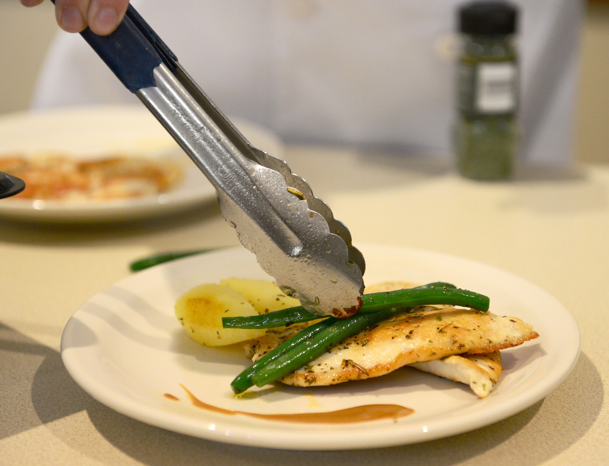 Airman 1st Class Angela Berg, 31st Force Support Squadron food services journeyman, plates a dish during a cooking class she hosted, July 24, 2014, at Aviano Air Base, Italy. Berg was recently a student at the Department of Defense’s Advanced Culinary Arts Training Center located at Fort Lee, Va, where she prepared an eight course meal for 24 VIPs in order to complete the class. (U.S. Air Force photo/Senior Airman Matthew Lotz)