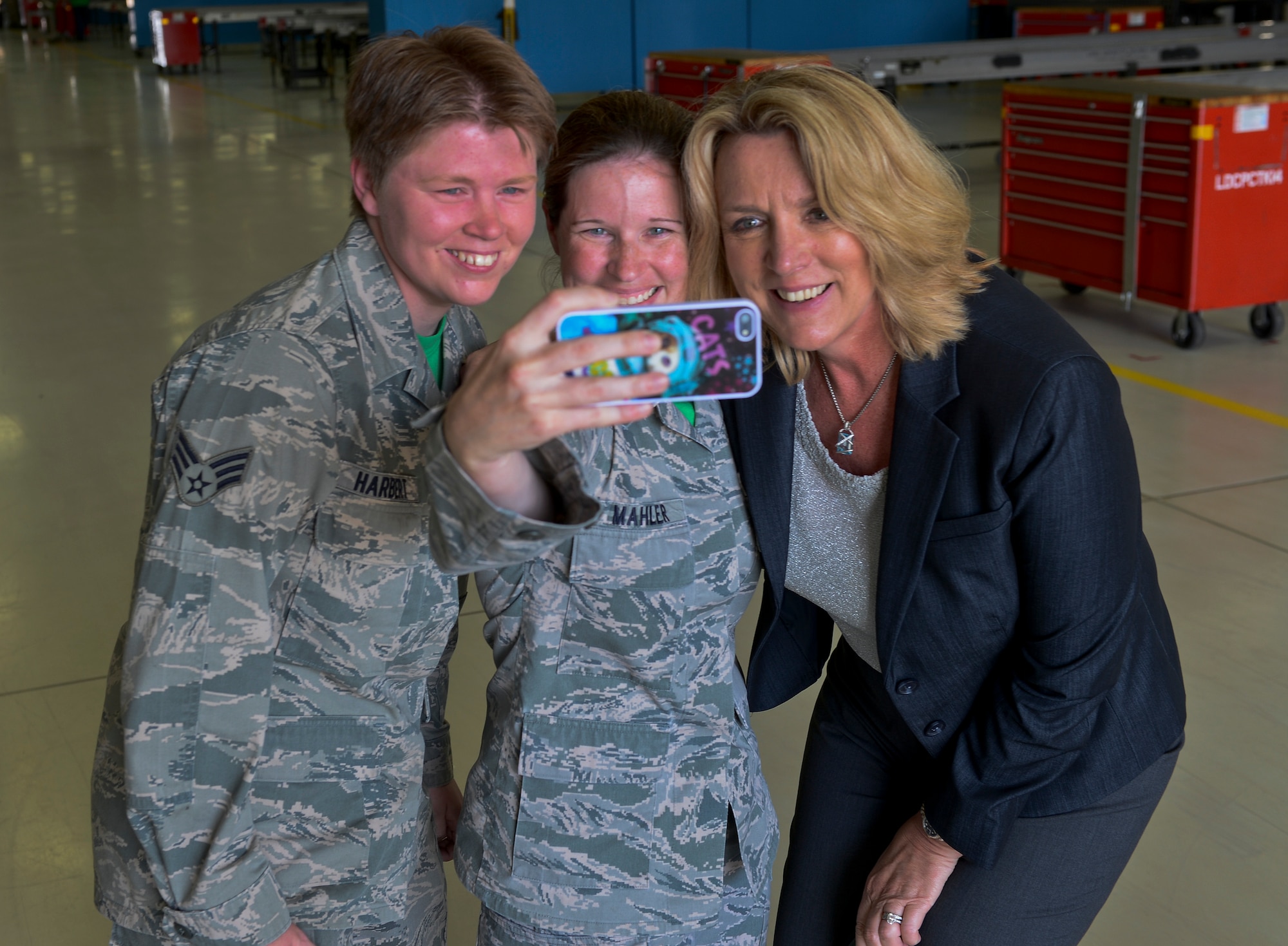 Secretary of the Air Force Deborah Lee James takes a selfie with Master Sgt. Christine Mahler, 48th Component Maintenance Squadron acting propulsion flight chief, center, and Senior Airman Amanda Harbert, 48th CMS aerospace propulsion journeyman, left, during her visit to the propulsion shop at Royal Air Force Lakenheath, England, July 18, 2014. James visited numerous squadrons to interact with Airmen and learn more about the 48th Fighter Wing’s mission. 48th CMS Airmen wear green squadron t-shirts every Friday. (U.S. Air Force photo by Airman 1st Class Trevor T. McBride/Released)