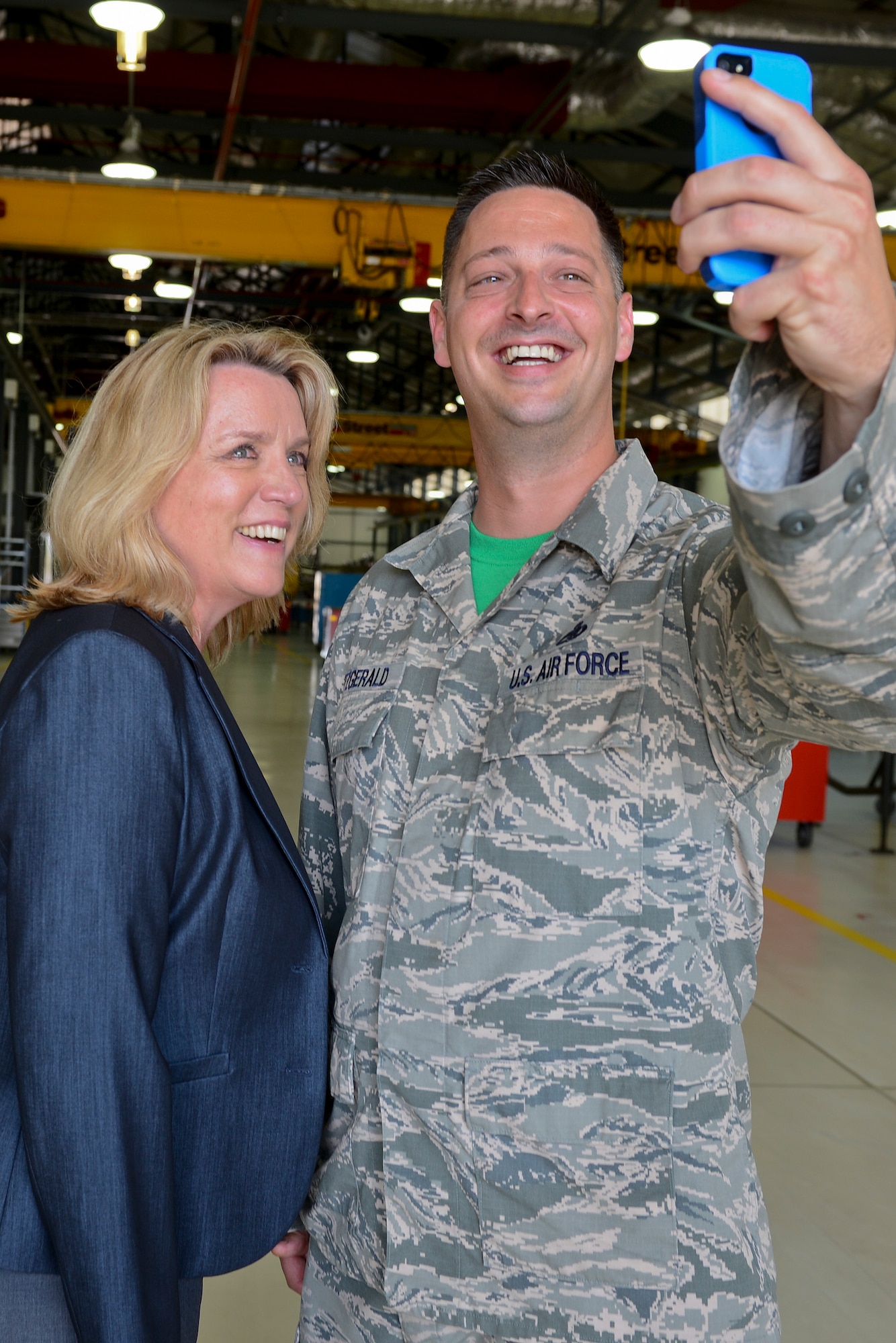 Secretary of the Air Force Deborah Lee James takes a selfie with Master Sgt. Scott Fitzgerald, 48th Component Maintenance Squadron propulsion flight superintendent, during her visit to the propulsion shop at Royal Air Force Lakenheath, England, July 18, 2014. James visited numerous squadrons to interact with Airmen and learn more about the 48th Fighter Wing’s mission. 48th CMS Airmen wear green squadron t-shirts every Friday. (U.S. Air Force photo by Airman 1st Class Trevor T. McBride/Released)