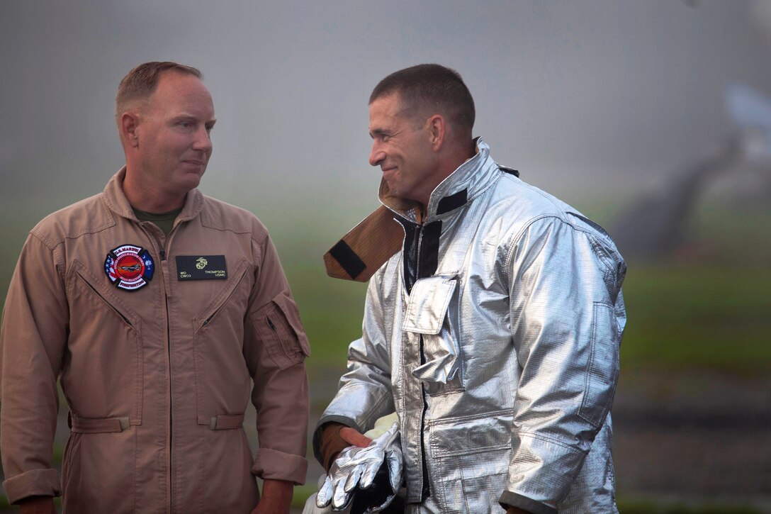Marine Corps Lt. Col. Brian W. Foster, right, speaks with Marine Corps Chief Warrant Officer 3 William D. Thompson during training to fight fires and rescue aircraft on Marine Corps Air Station Beaufort, S.C., July 22, 2014. Foster commands Headquarters Squadron and Thompson commands the aircraft rescue  unit. 