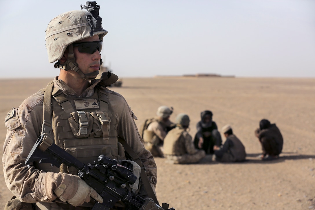 U.S. Marine Corps Lance Cpl. Joseph Friedlander provides security for U.S. Marine Corps Cpl. Justin Hinckley as he talks to an Afghan  family from the Washer district during a security patrol in Afghanistan's Helmand Province, July 16, 2014. Friedlander, a driver, and Hinckley, a team leader, are assigned to Weapons Company, 1st Battalion, 2nd Marine Regiment.