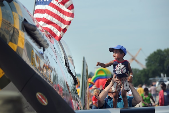 Four-year-old James Aldendifer is lifted onto the wing of the P-51 Mustang by his father Mark while attending the 2014 Defenders of Freedom Open House and Air Show July 19, 2014, on Offutt Air Force Base, Neb. Record crowds gathered at Offutt AFB to attend the event. (U.S. Air Force photo/Josh Plueger)