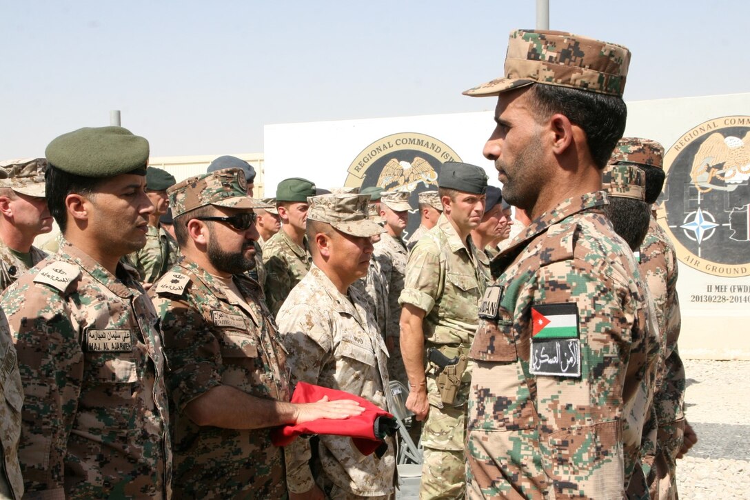 A soldier with the Kingdom of Jordan's army presents the Jordan flag to Lt. Col. Mohammed A. Aljarrah, commanding officer of the Jordanian Army with Regional Command (Southwest), during a flag-lowering ceremony aboard Camp Leatherneck, Helmand province, Afghanistan, July 23, 2014. The ceremony marked the end of mission for the Jordanian army serving with RC(SW).