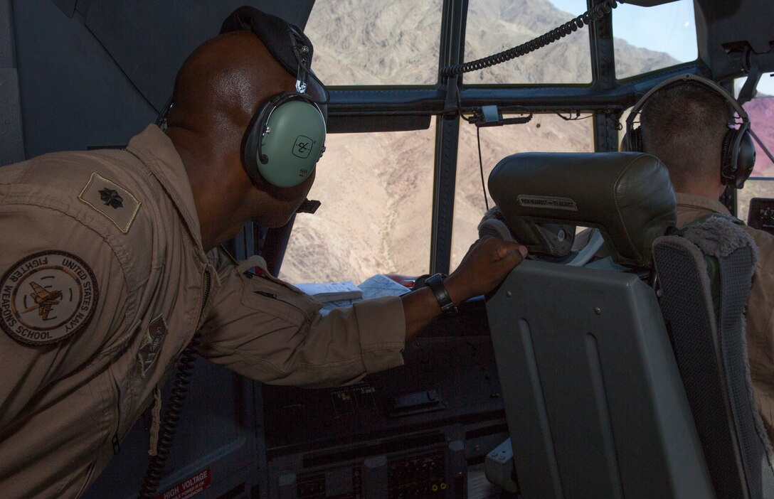 Navy Cmdr. Ellis Gayles, left, aeromedical safety officer and director of safety and standardization with 3rd Marine Aircraft Wing, looks out the cockpit window of a KC-130J Hercules during low-level tactical navigation training outside of Yuma, Ariz., July 24. Gayles attended the training flight to observe the pilots and crews in order to better understand what they endure during flight. 