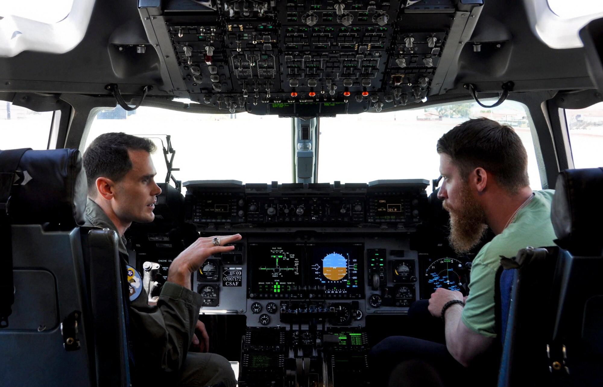Sean Doolittle, Oakland Athletics pitcher, learns about the C-17 Globemaster III July 21 at Travis Air Force Base. Capt. Luke Robertson, 21st Airlift Squadron weapons and tactics flight commander, explains the control panels inside the flight deck. (U.S. Air Force photo by Airman 1st Class Amber Carter)