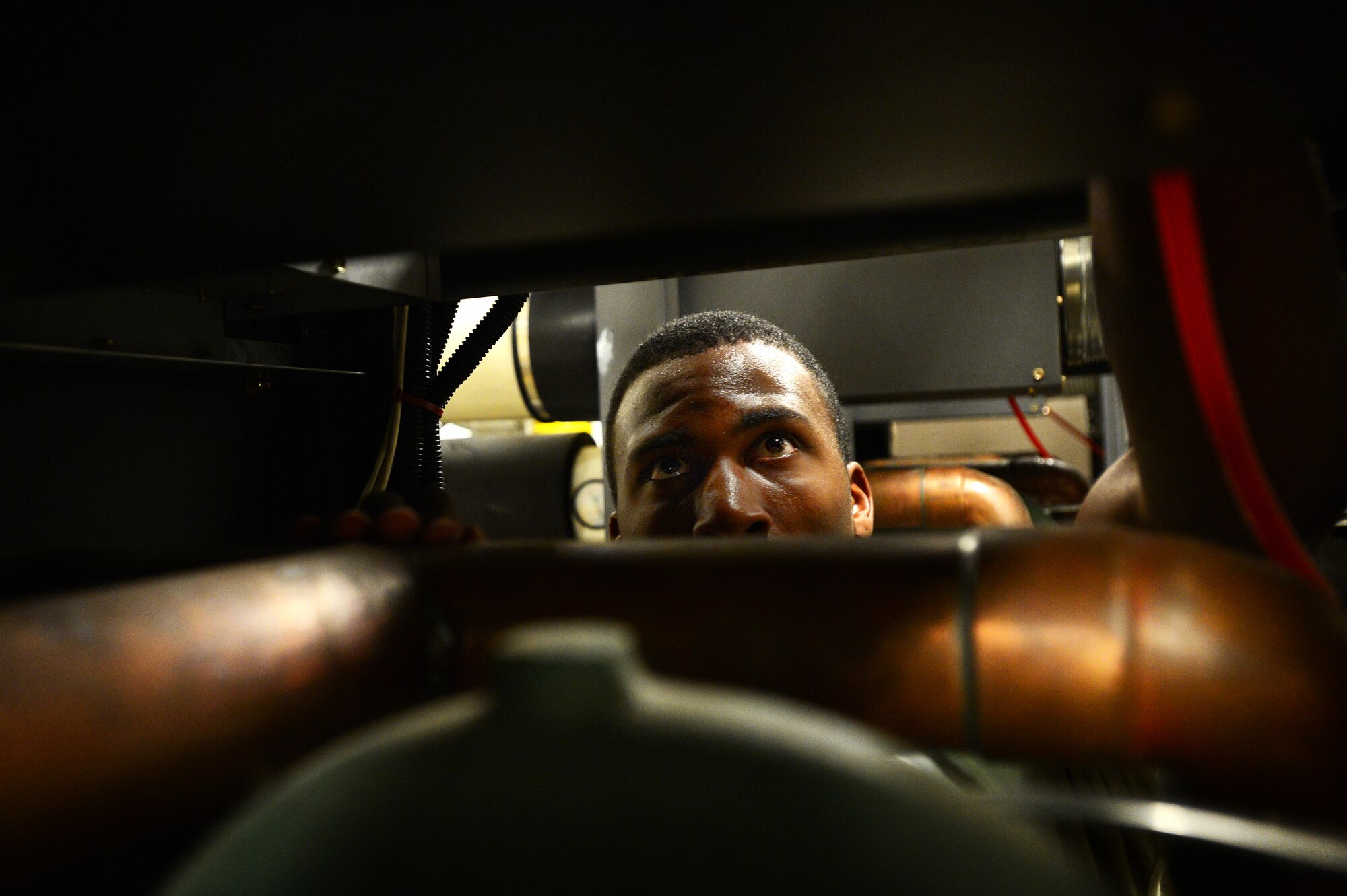 U.S. Air Force Senior Airman Jarell Rose, 20th Civil Engineer Squadron heating, ventilation, air conditioning and refrigerating journeyman, inspects a boiler at Shaw Air Force Base, S.C., July 23, 2014. While trying to get it running again, Rose inspected the electrical wires on the inside of the broiler while searching for the cause of the problem. (U.S. Air Force photo by Airman 1st Class Jensen Stidham/Released) 